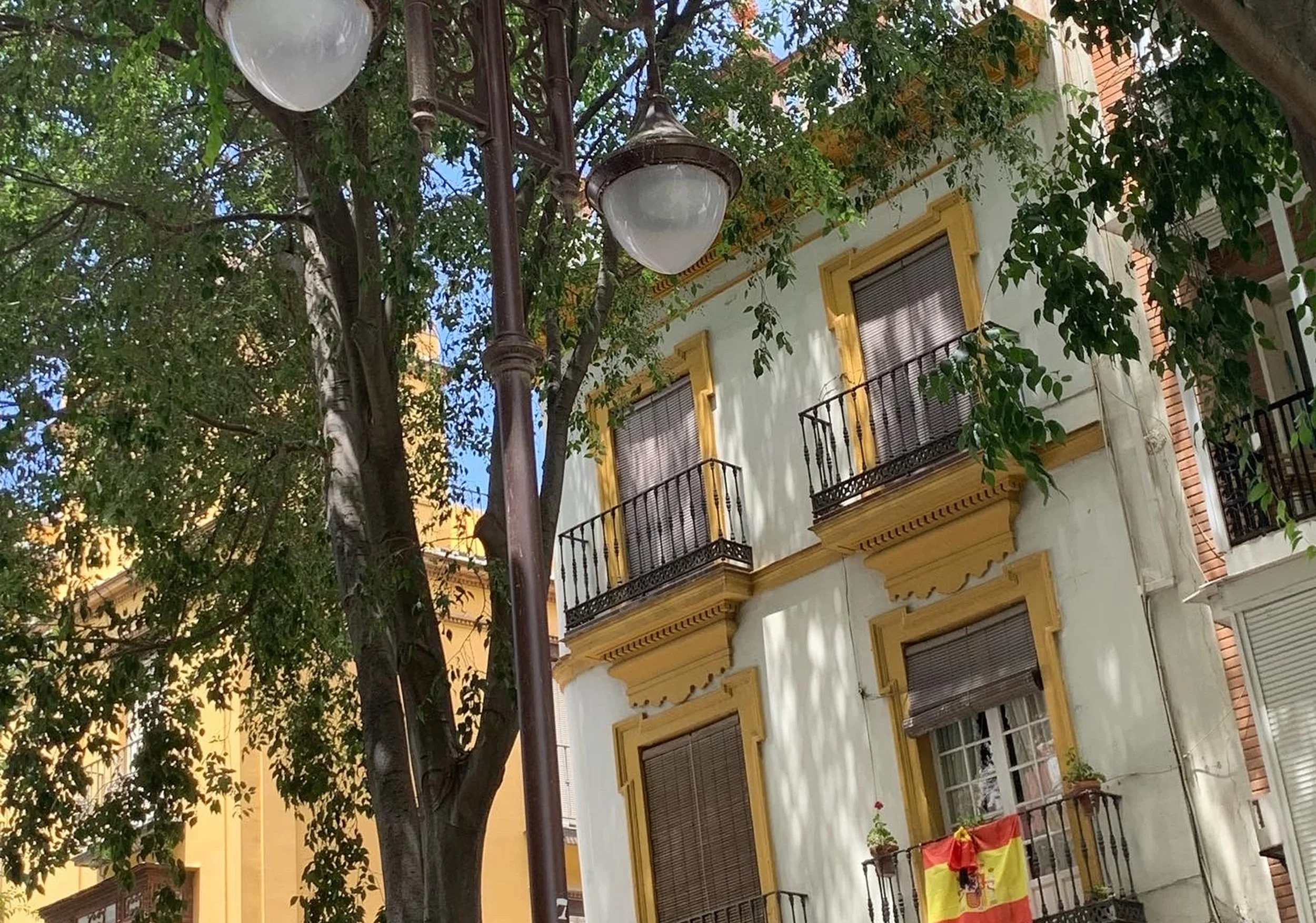 spanish flag out of apartment in seville light green building