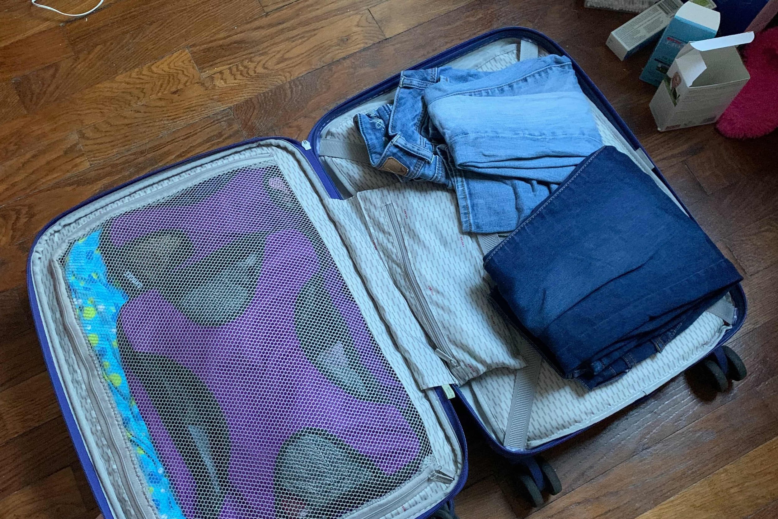jeans and packing cubes inside purple carry on suitcase