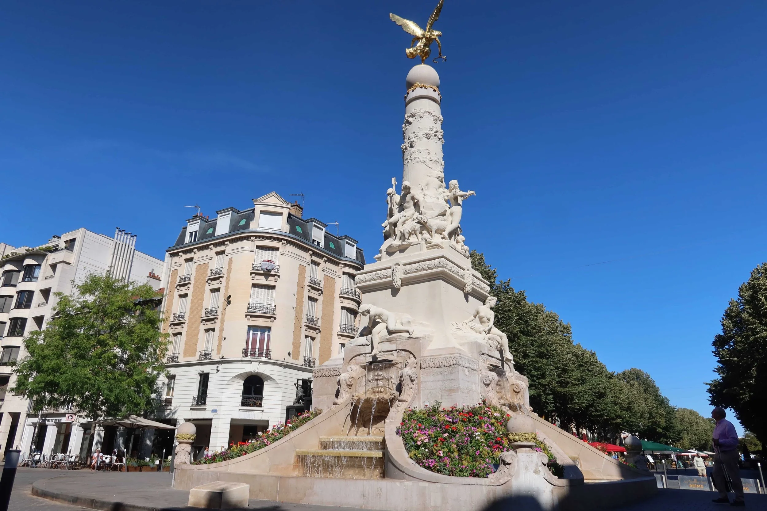 gold fountain on busy street with cafes