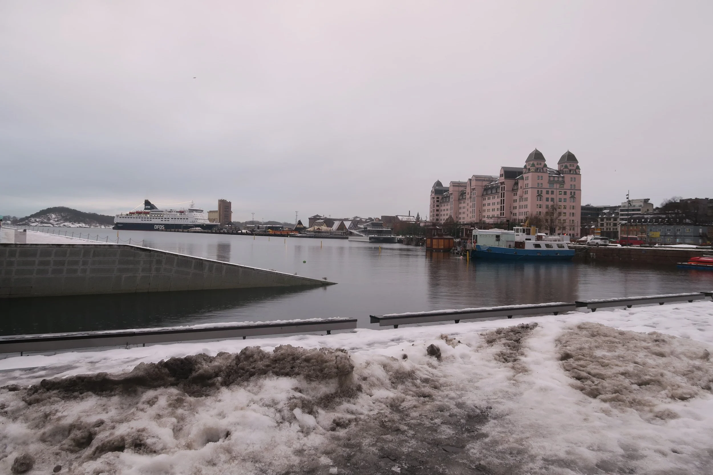pink building on water with dirty snow and white sky