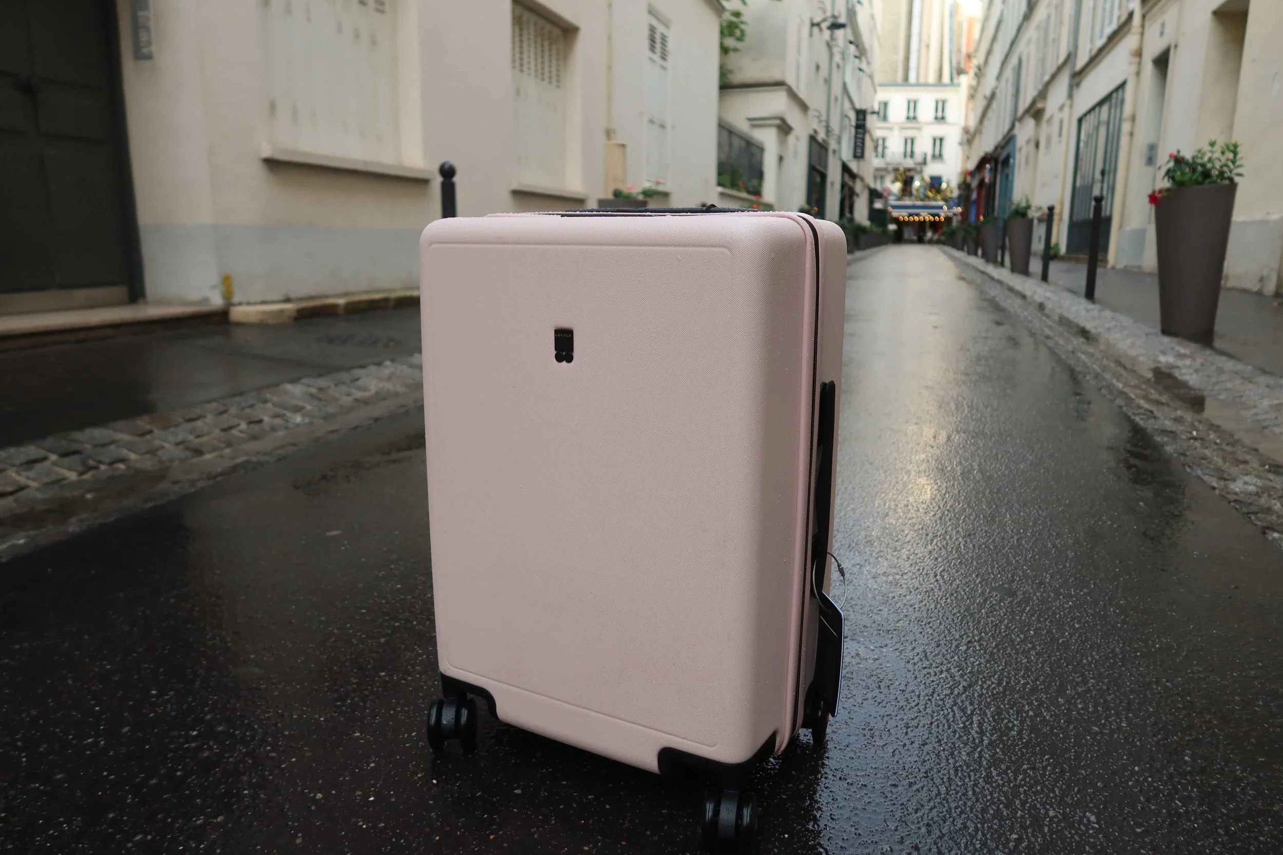 light pink suitcase on quiet street in paris