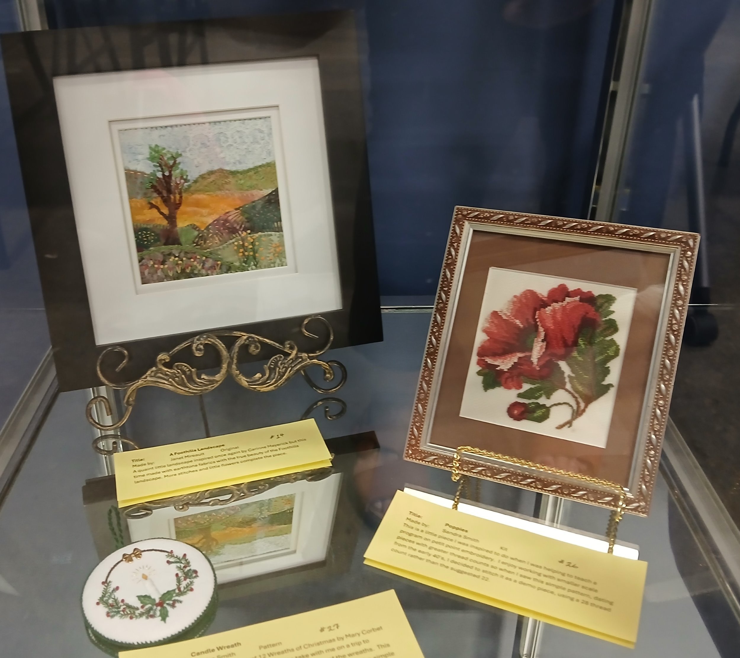 A Foothills Landscape (upper left) Designed & stitched by Janet M. / Fabric landscape with earth tone fabrics, stitching & little flowers Poppies (middle right) Stitched by Sandra S / Unknown designer, pattern from the 1940’s / Petit