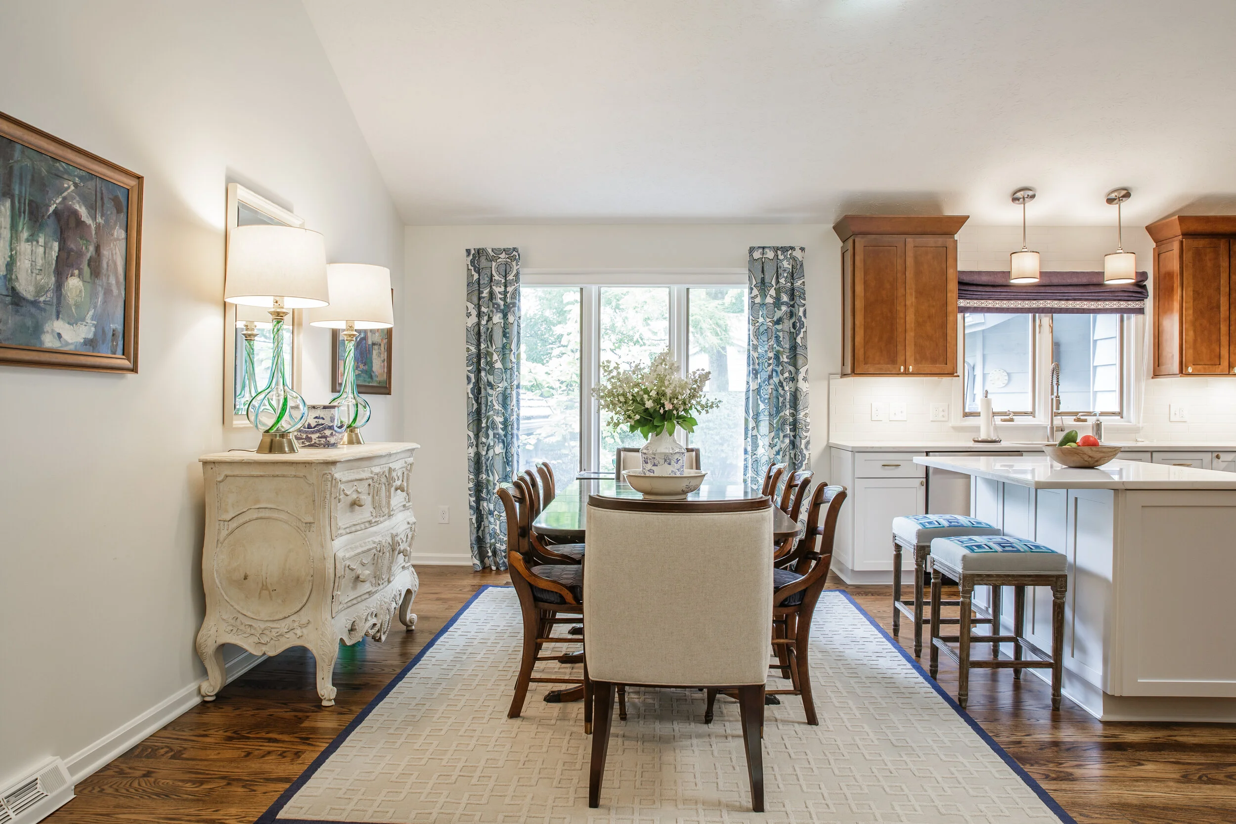 Classic geometric patterns in the custom area rug work mirror the quilting squares we applied to counter stools. Modern artwork &amp; the great find of Glass lamps bring teal to the room.