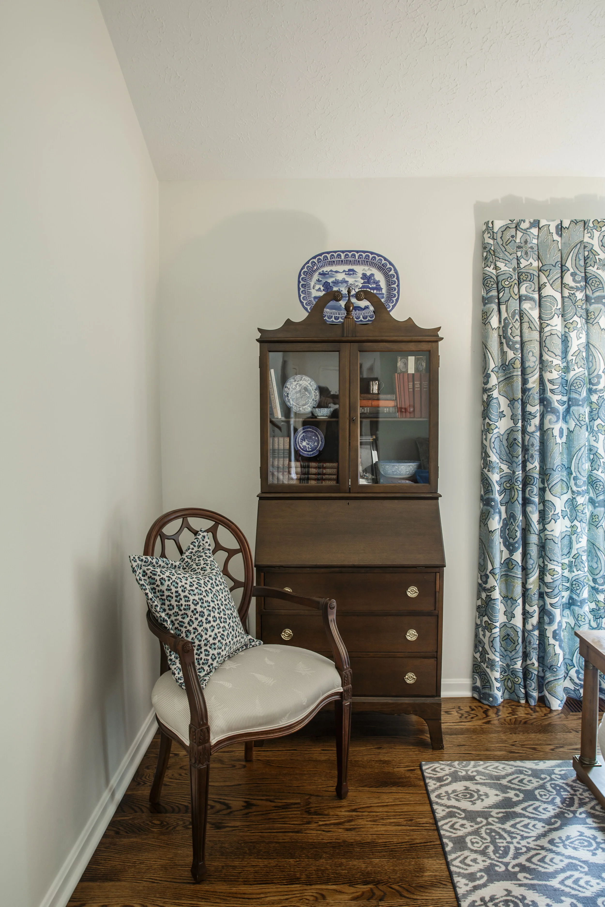 This traditional mahogany secretary was the perfect place to introduce our client’s amazing antique collection of blue &amp; white china. We added an updated leopard pattern with our modern digital print for the draperies.