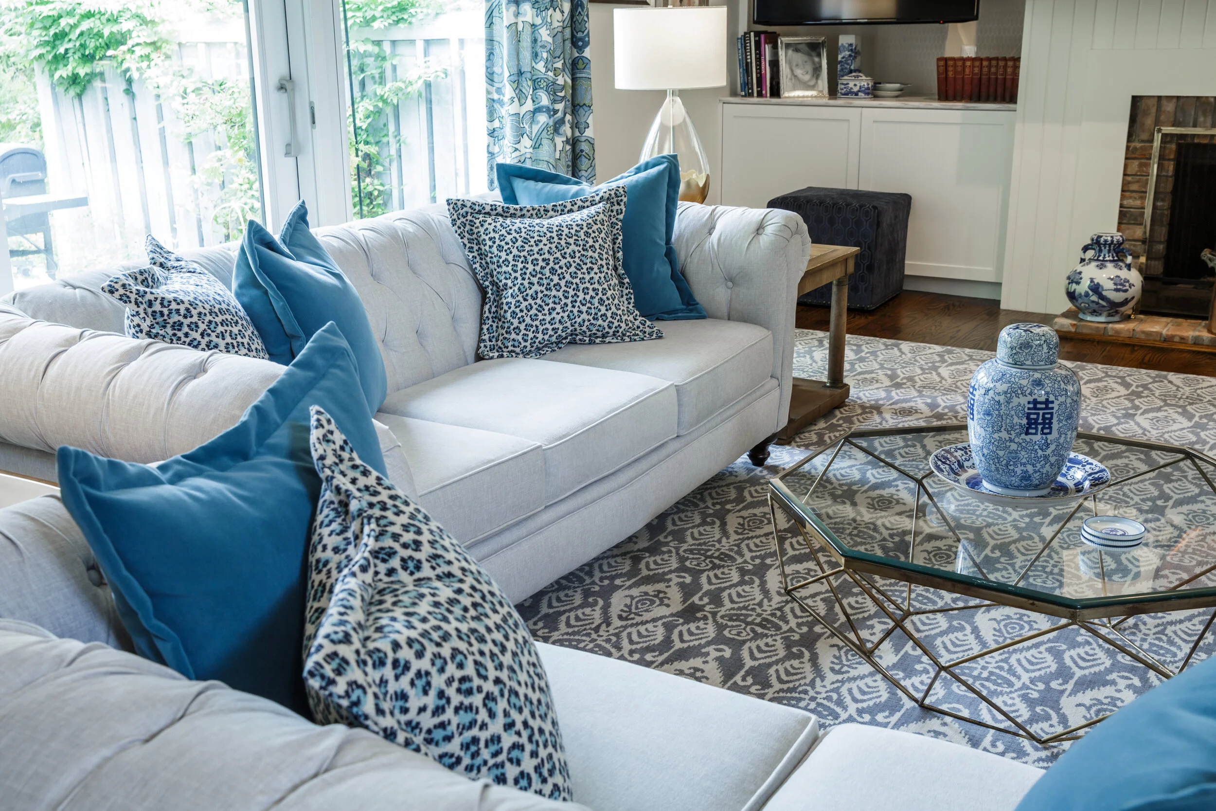 A modern shaped glass cocktail table mixed with tufted chesterfield sofas added an element of surprise and interest to the room.