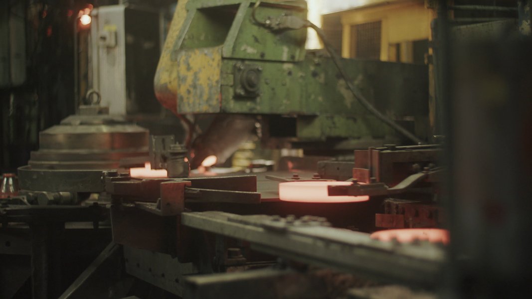 Industrieanlage mit glühenden Metallteilen und Maschinen