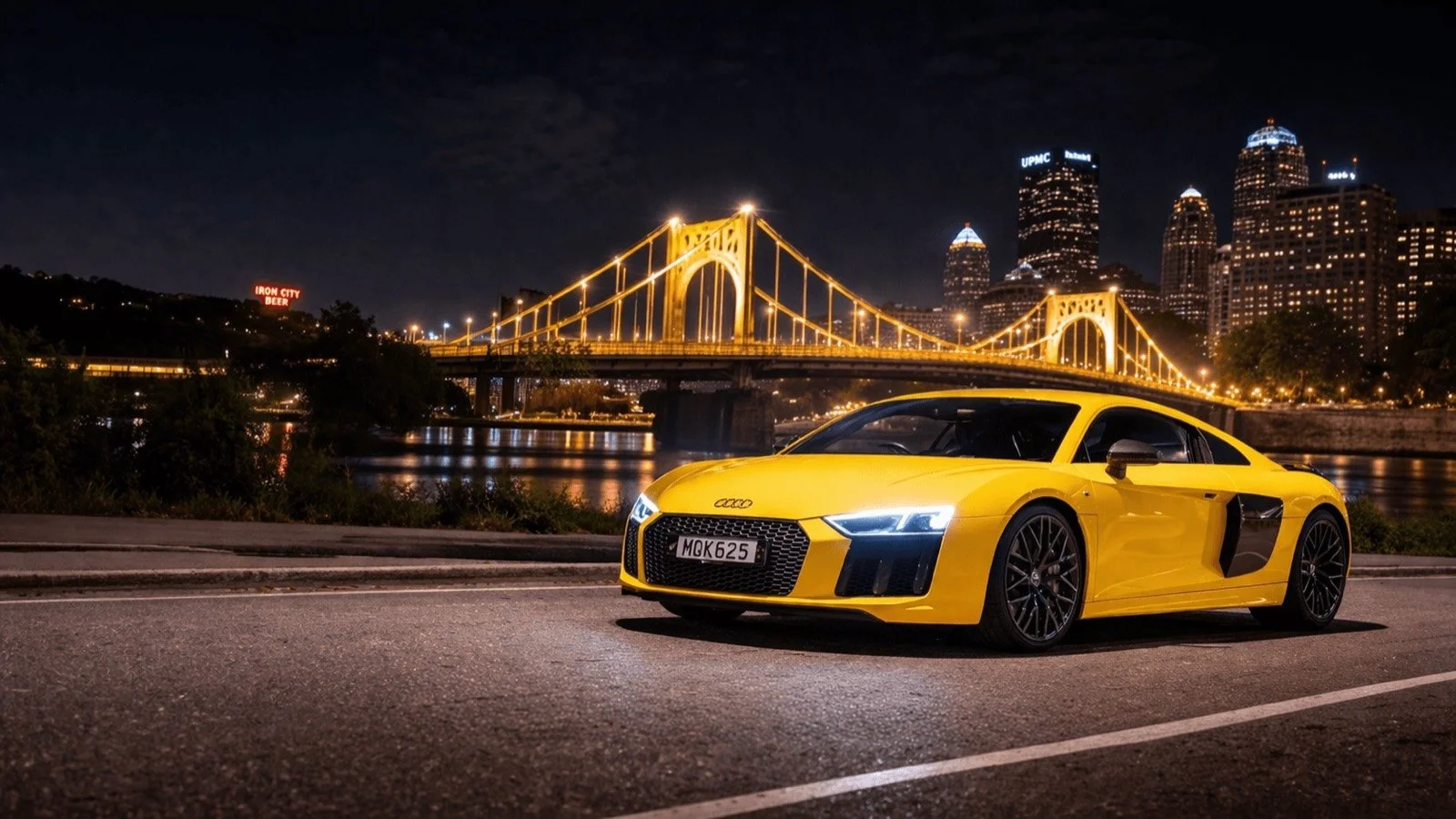 Yellow sports car with tinted windows near a Pittsburgh bridge at night in Pittsburgh, PA