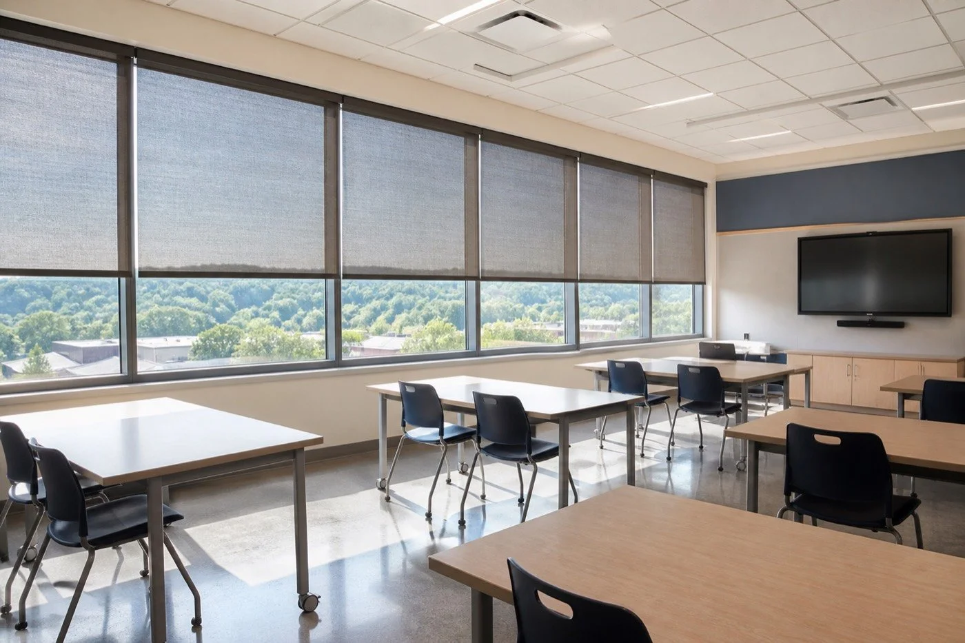 Commercial solar roller shades reducing glare in a modern school classroom.
