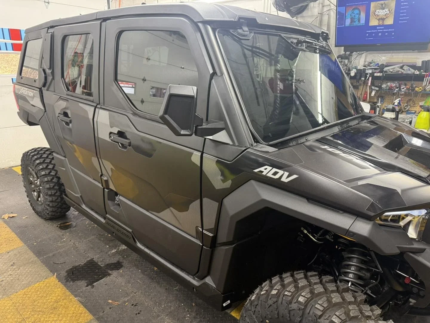 A black off-road utility vehicle with large tires inside a workshop or garage.