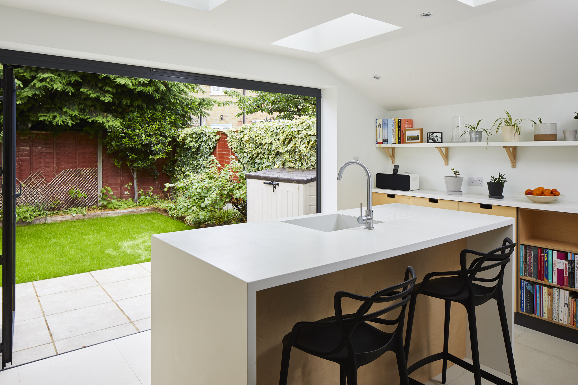 Unique kitchen design in East London - kitchen island with sink and backdrop of a sunny garden.