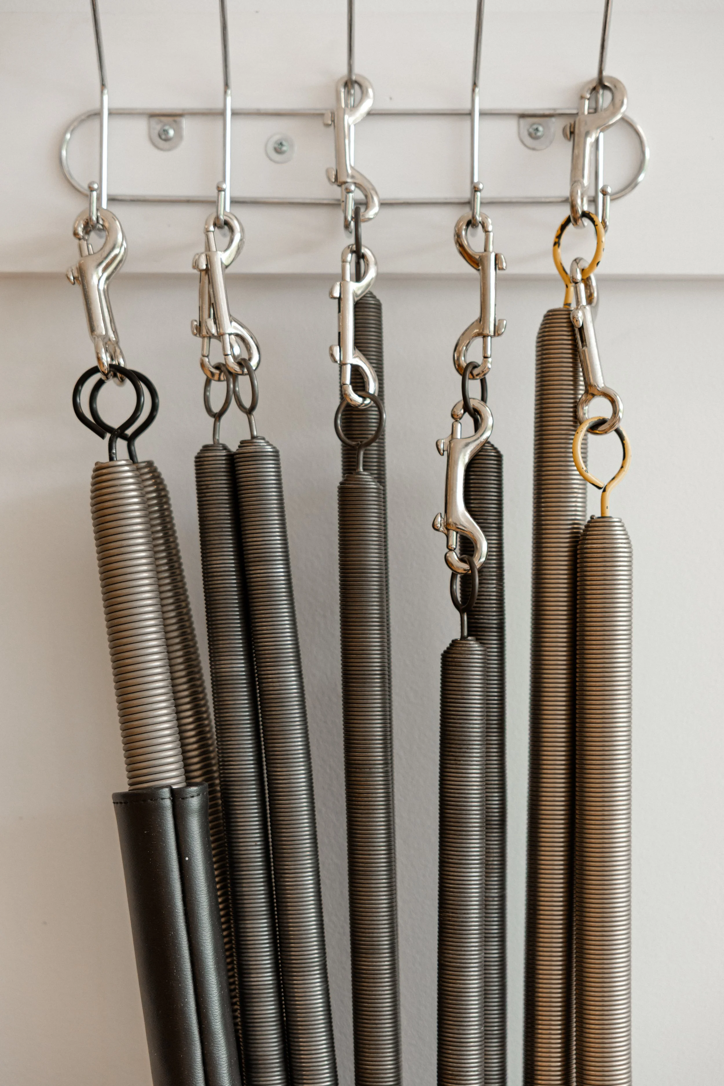 Jump rope handles hanging on a wall-mounted rack.