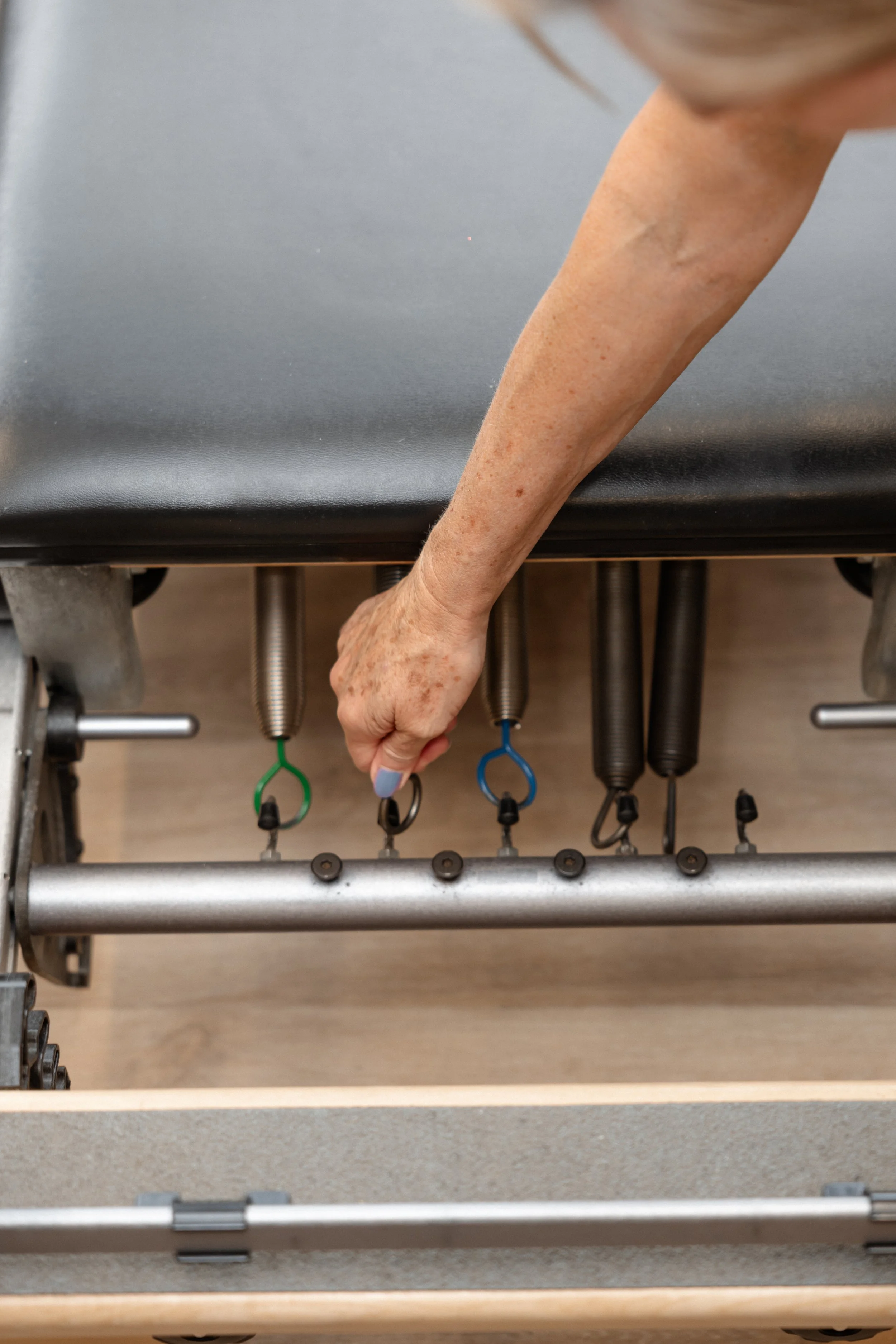 Close-up of a person's arm reaching and adjusting control levers on a hospital bed or medical equipment, with a focus on the hand and levers.