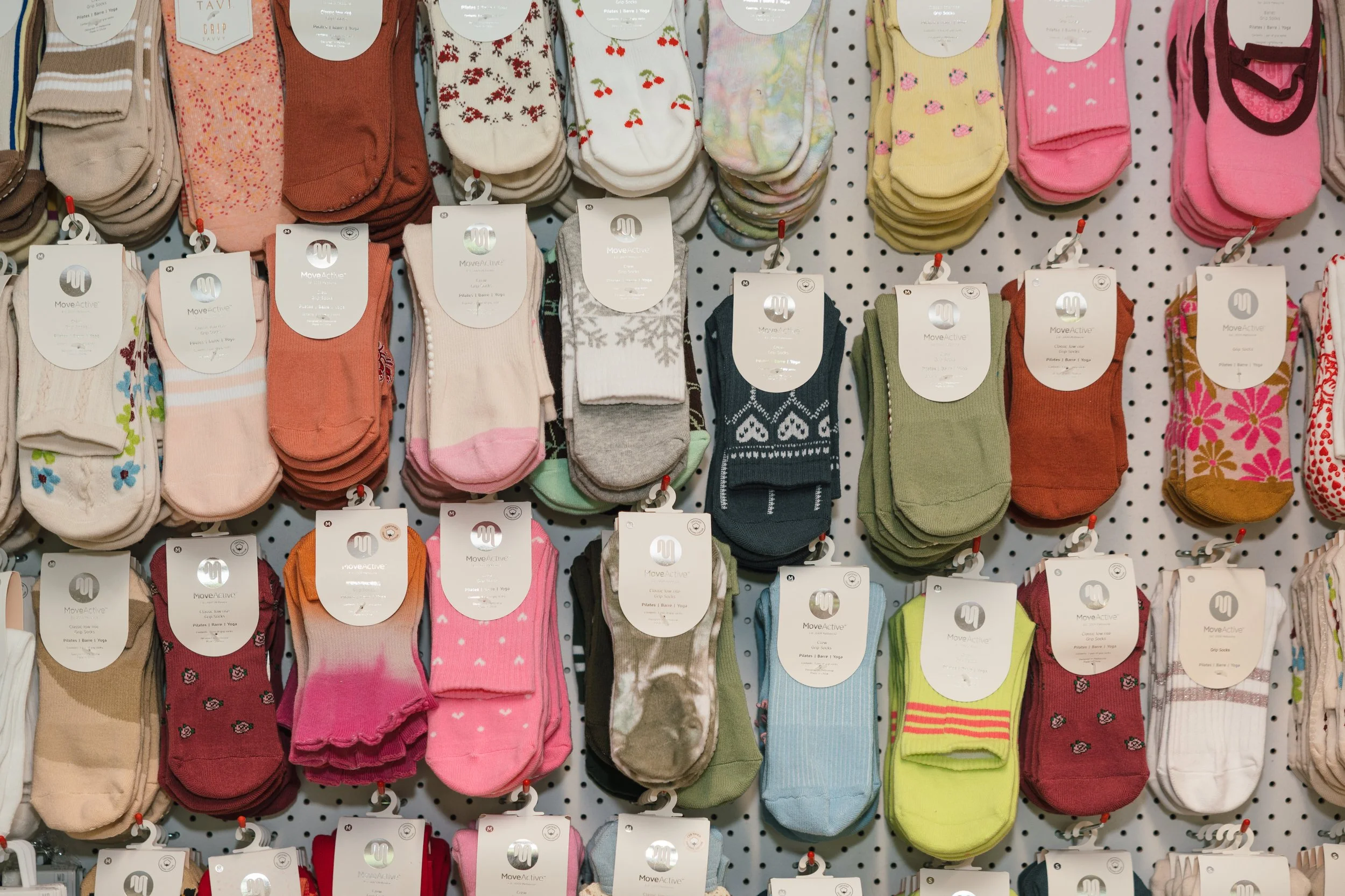 Display of colorful socks hanging on a pegboard in a retail store.