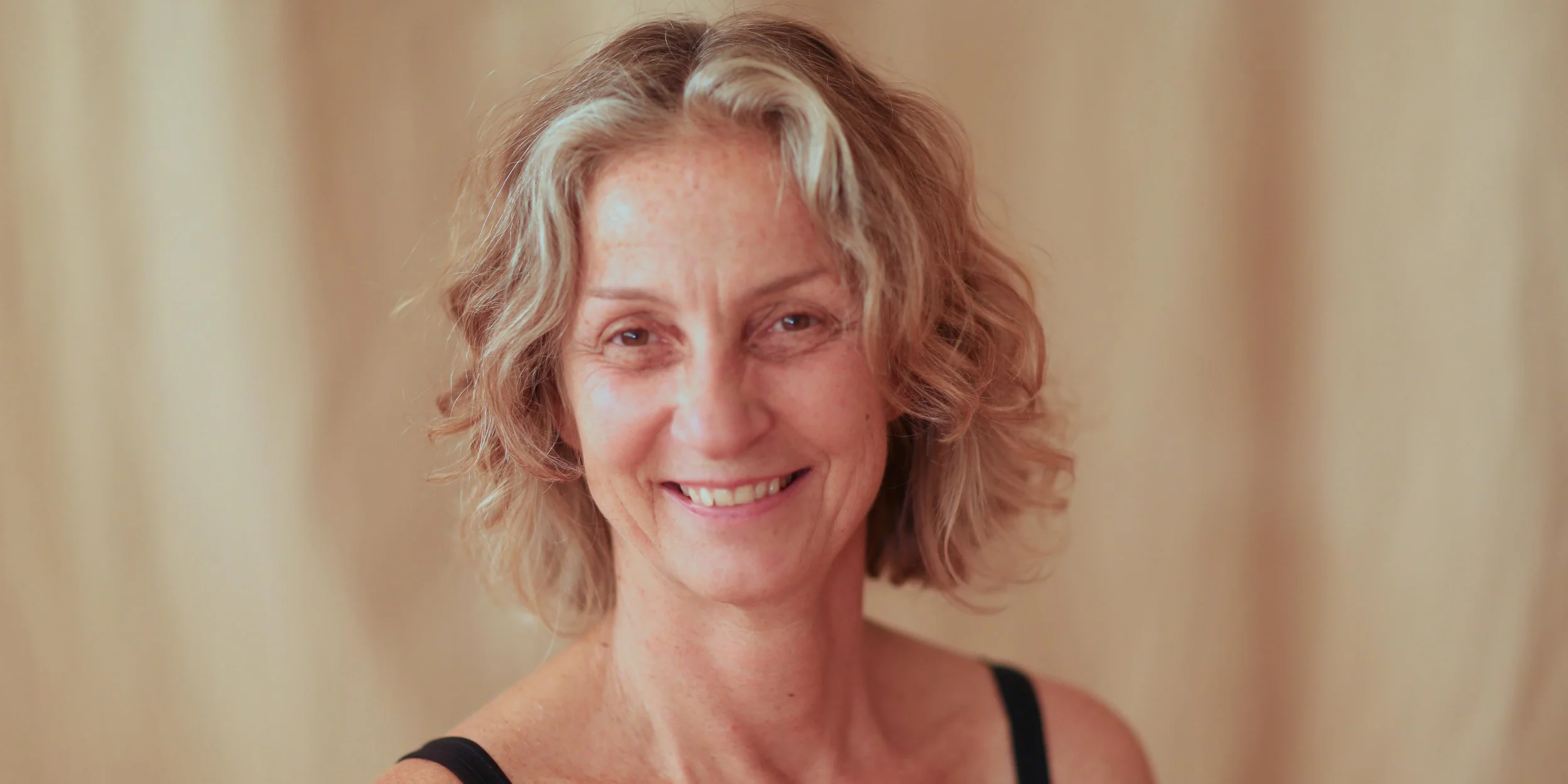 lächelnde Yogalehrerin vor hellem Hintergrund