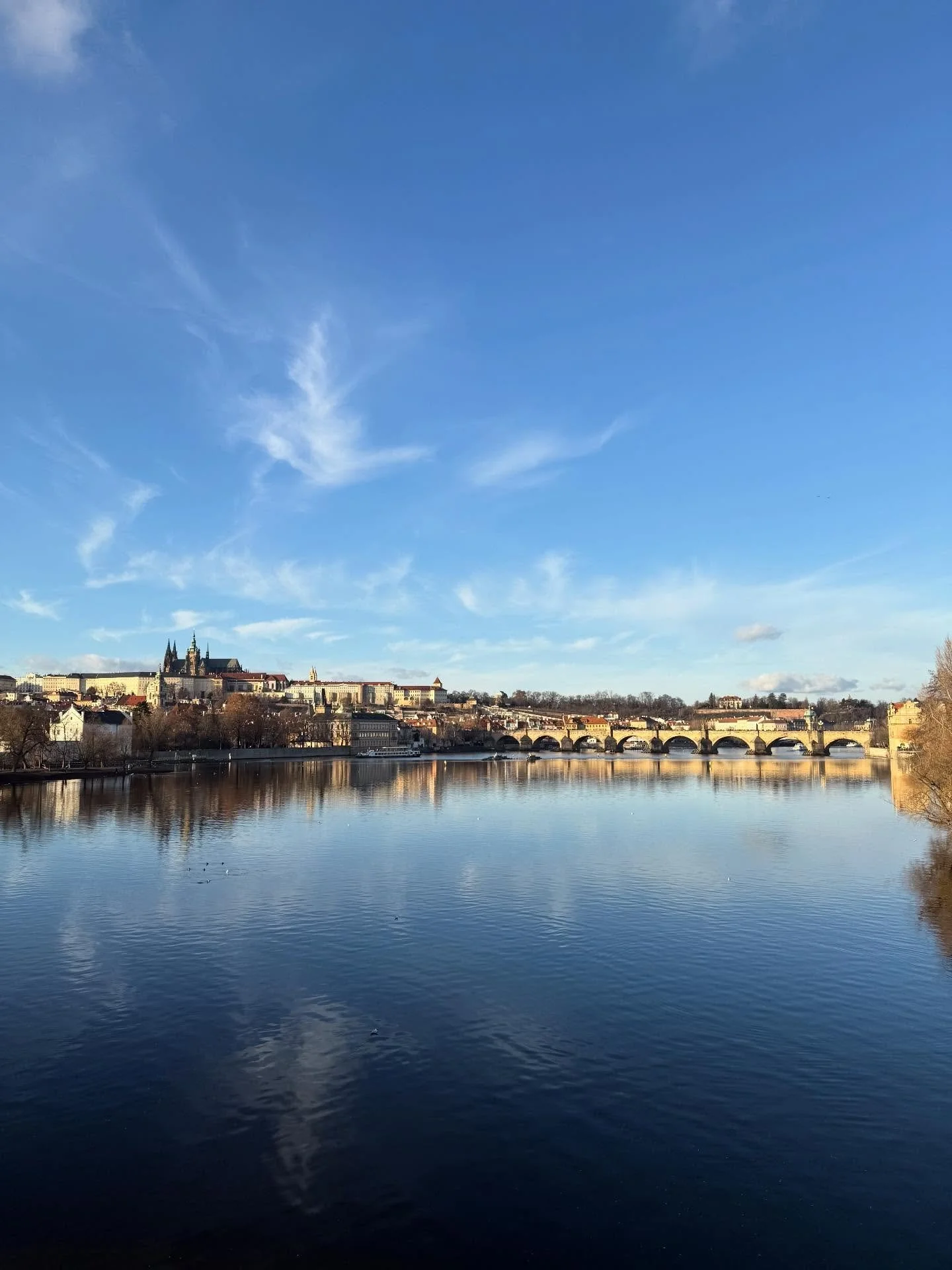 Trading prairie winds for cobblestones and the Vltava River. Prague is new to me, a city I&rsquo;ve wanted to visit for years, and I&rsquo;m here with time to write without the semester&rsquo;s pull.
The Christmas markets glow warm against the cold, 