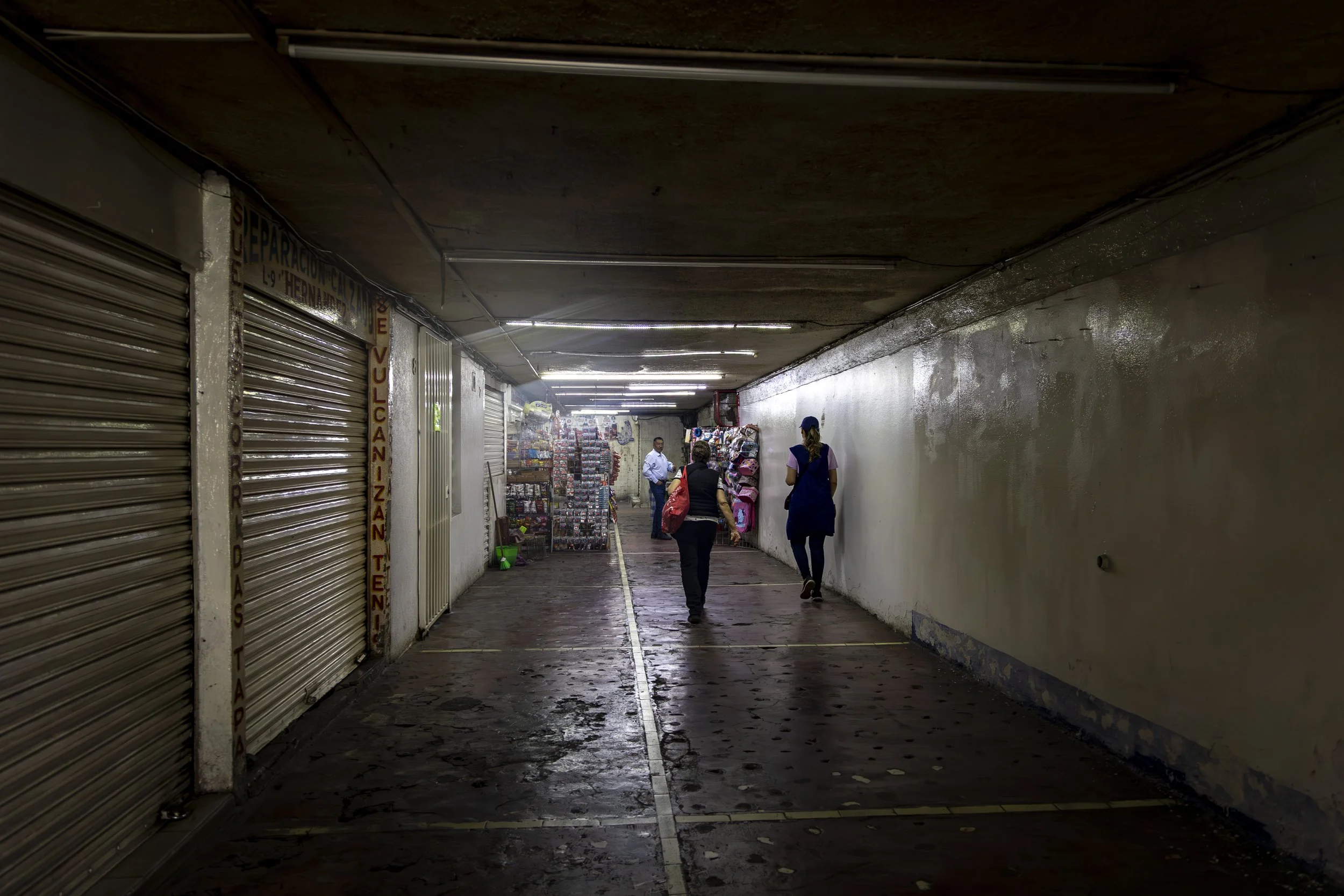   Un paso a desnivel bajo la avenida Calzada de Tlalpan, antes lleno de peatones, ahora está vacío, con pasillos desiertos y locales cerrados.  