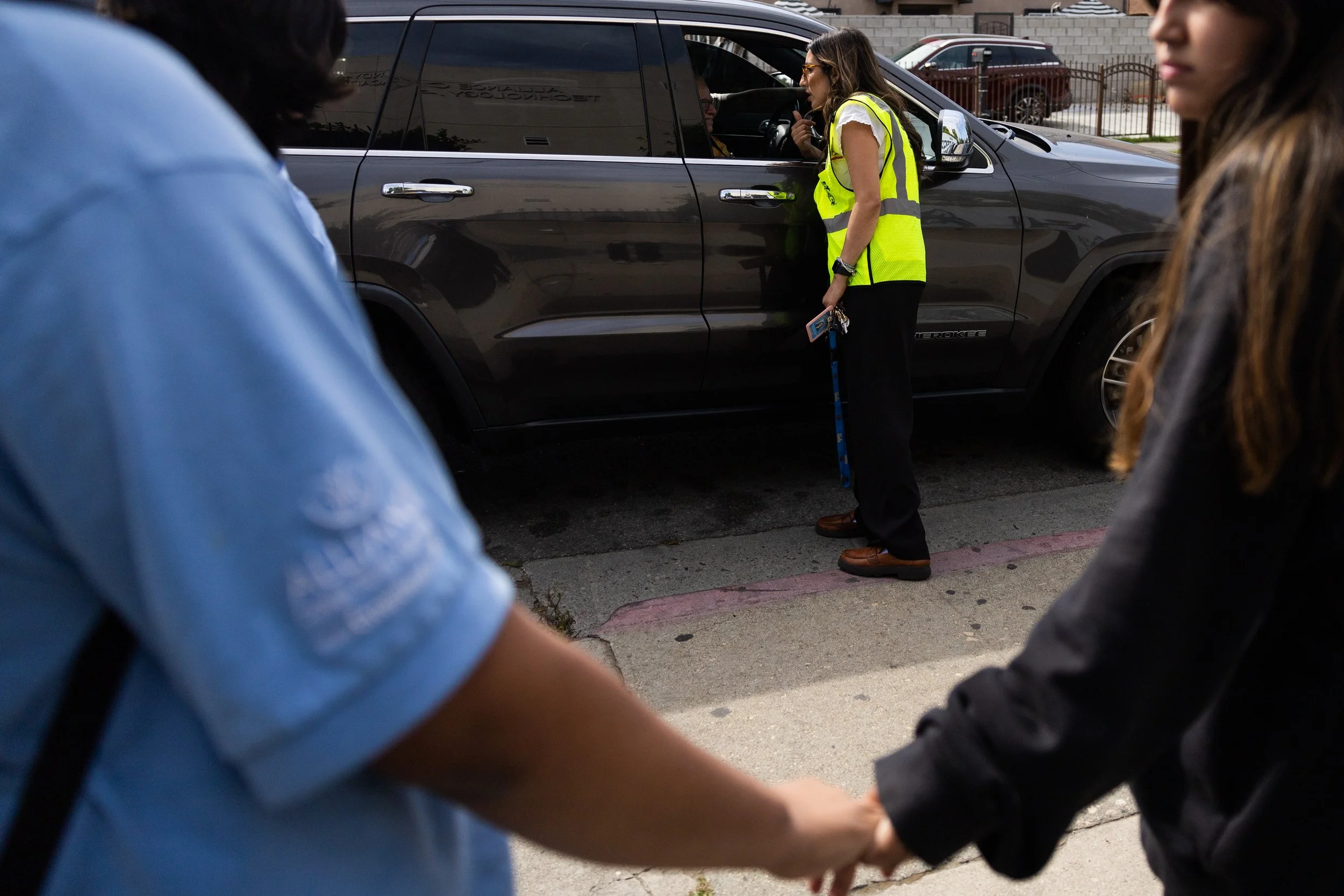   Students hold hands as Assistant Principal Lorena Reynoso speaks with a student’s guardian during after-school pickup.  
