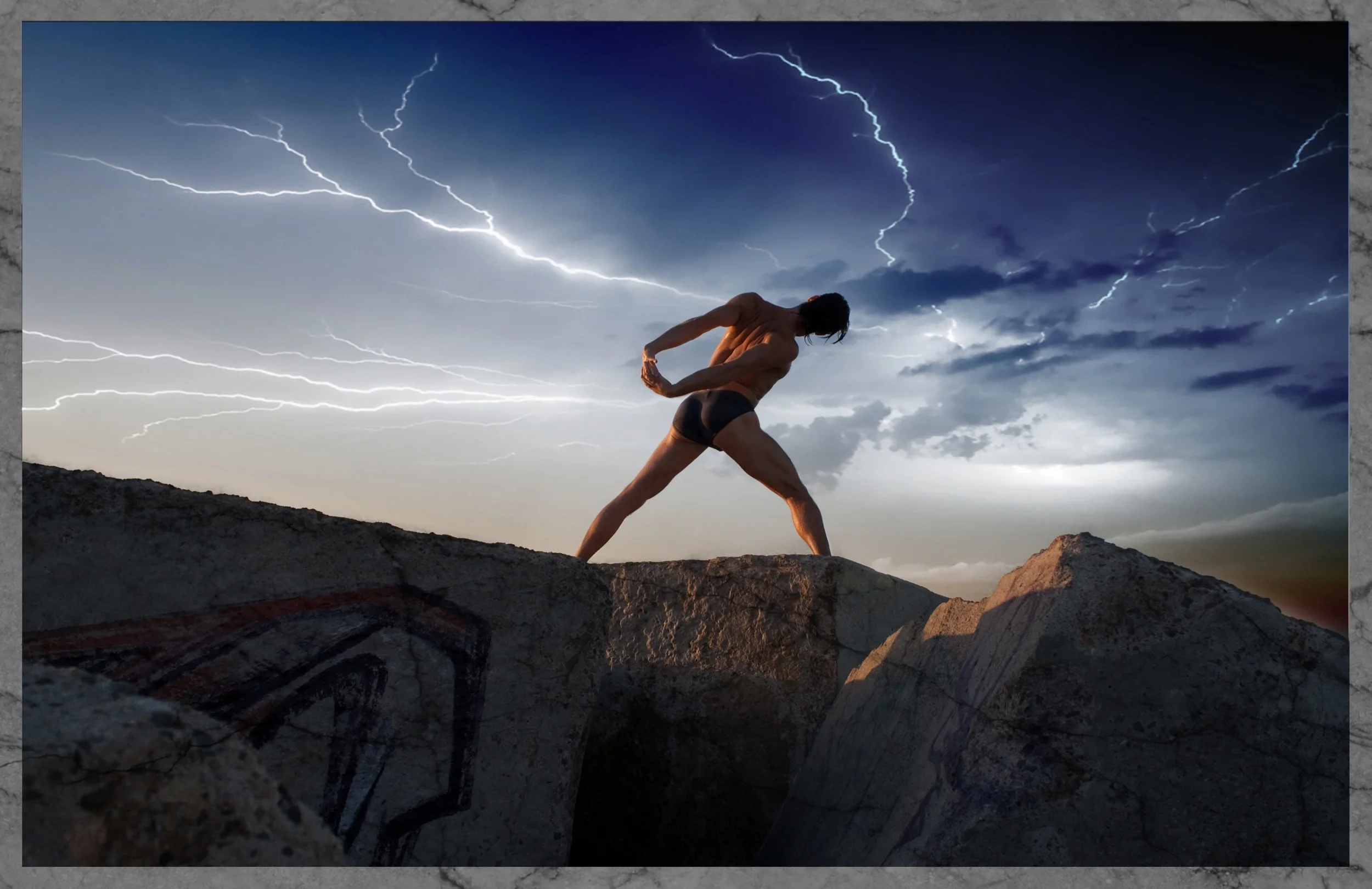A shirtless man wearing black shorts standing on a rocky ledge during a storm, with lightning striking in the sky behind him.