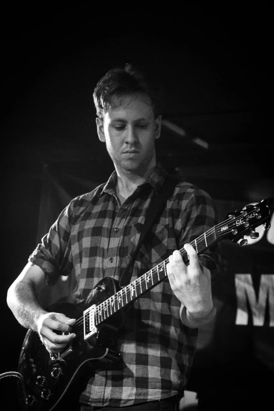 Ryder Howell, guitar teacher, performs on stage holding a black les paul guitar