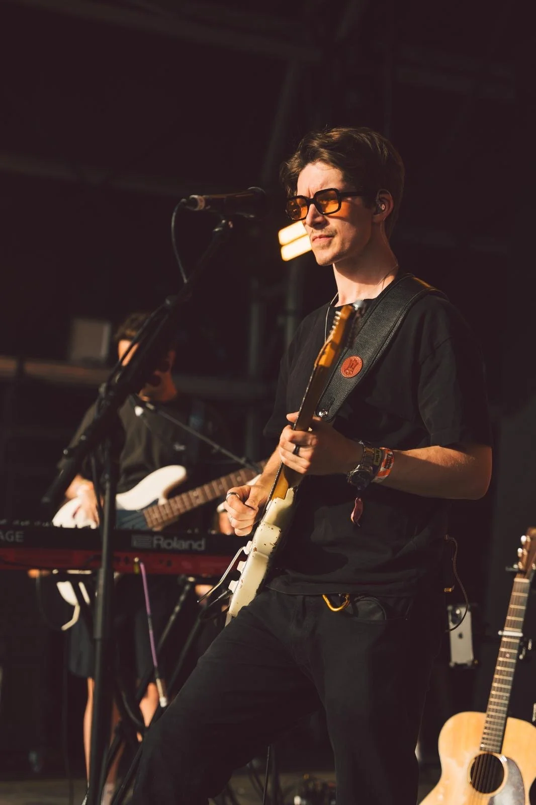 Callum Garland, Melbourne Guitar Teacher, performing on stage holding a white guitar