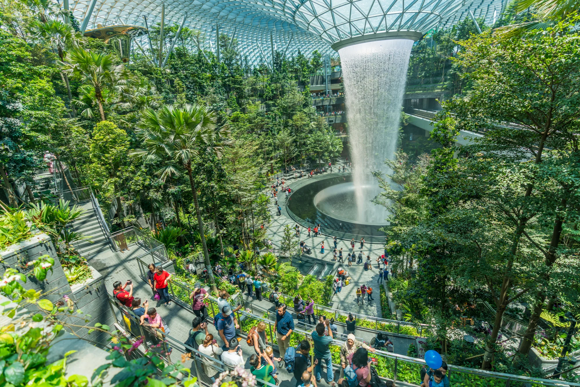 Passengers looking at the Rain Vortex located inside the Jewel at Changi Airport during a stopover in Singapore