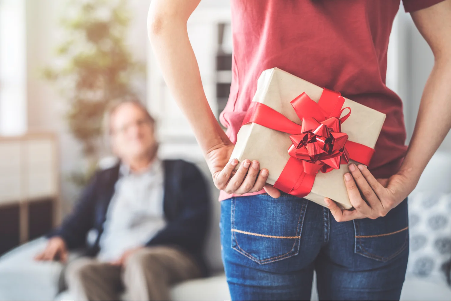 Young woman standing in front of her dad, holding a Father’s Day gift behind her back