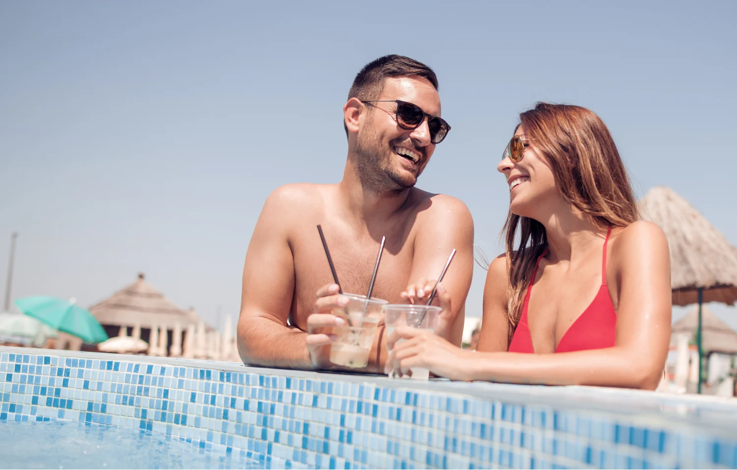 Young couple smiling at each other while drinking iced tea by the pool at an adults-only Bali resort