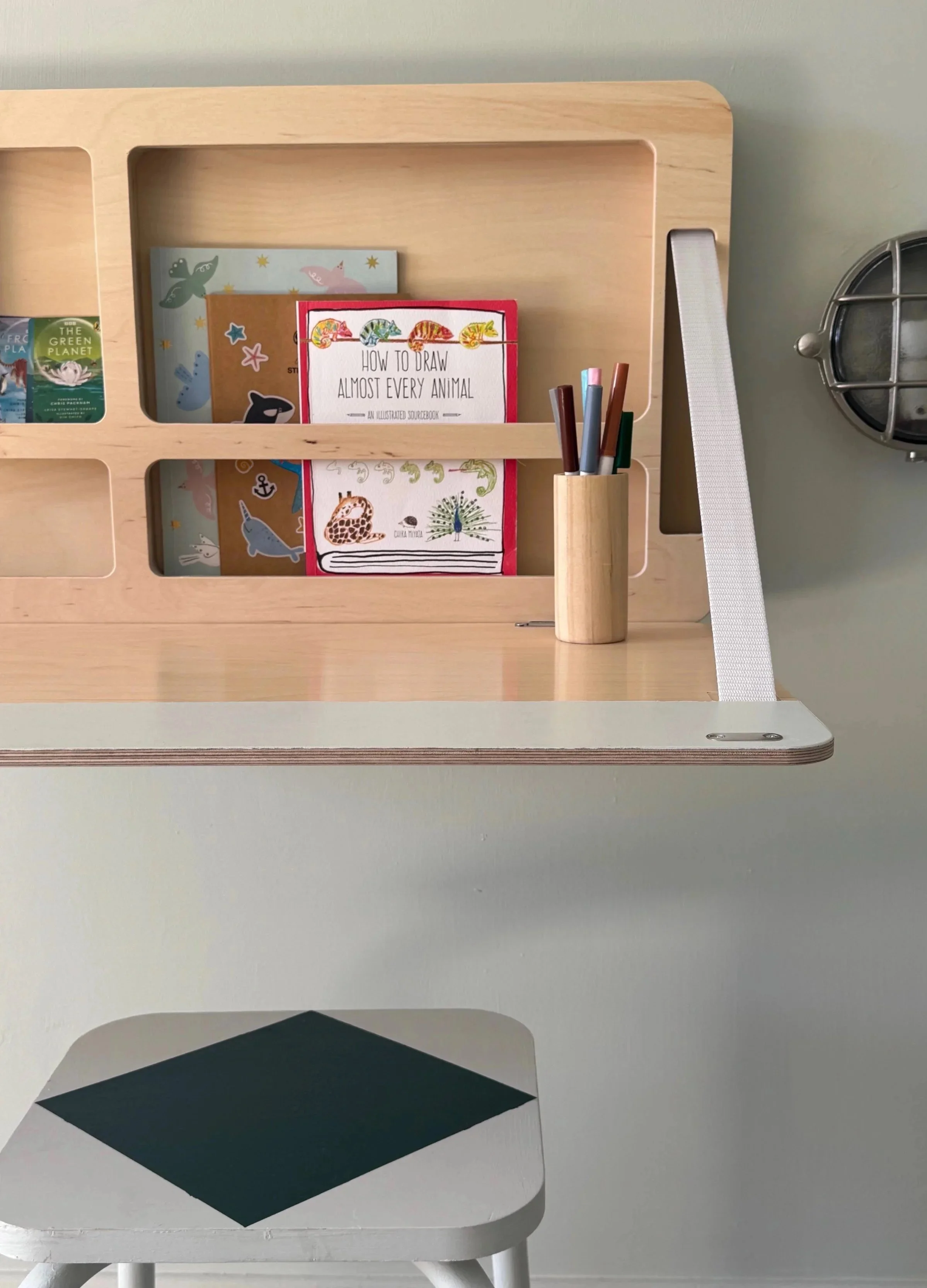 Children's desk folded down in plywood with notepads, pens and small stool with painted diamond on
