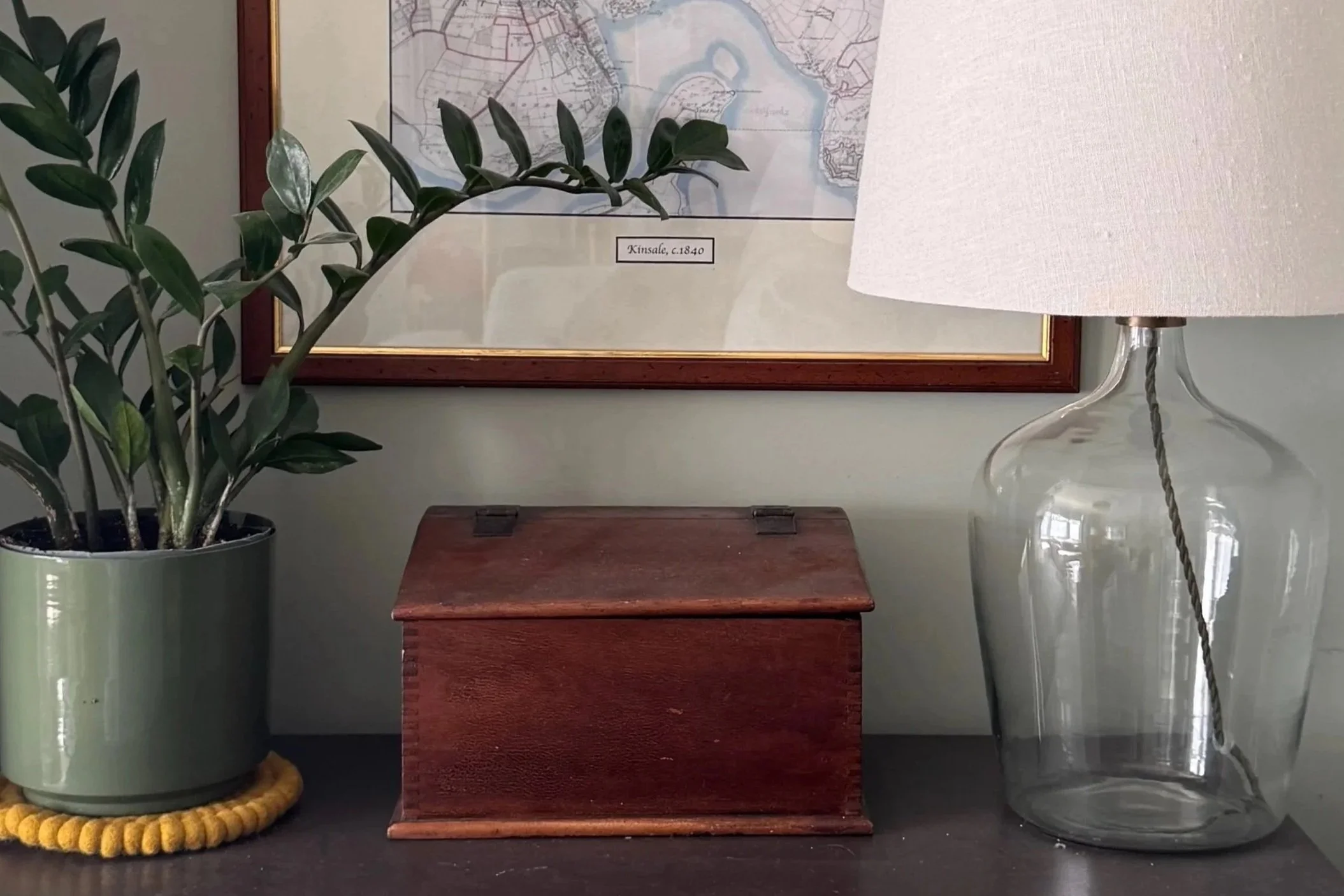 Table top with wooden box, house plant and clear glass lamp on