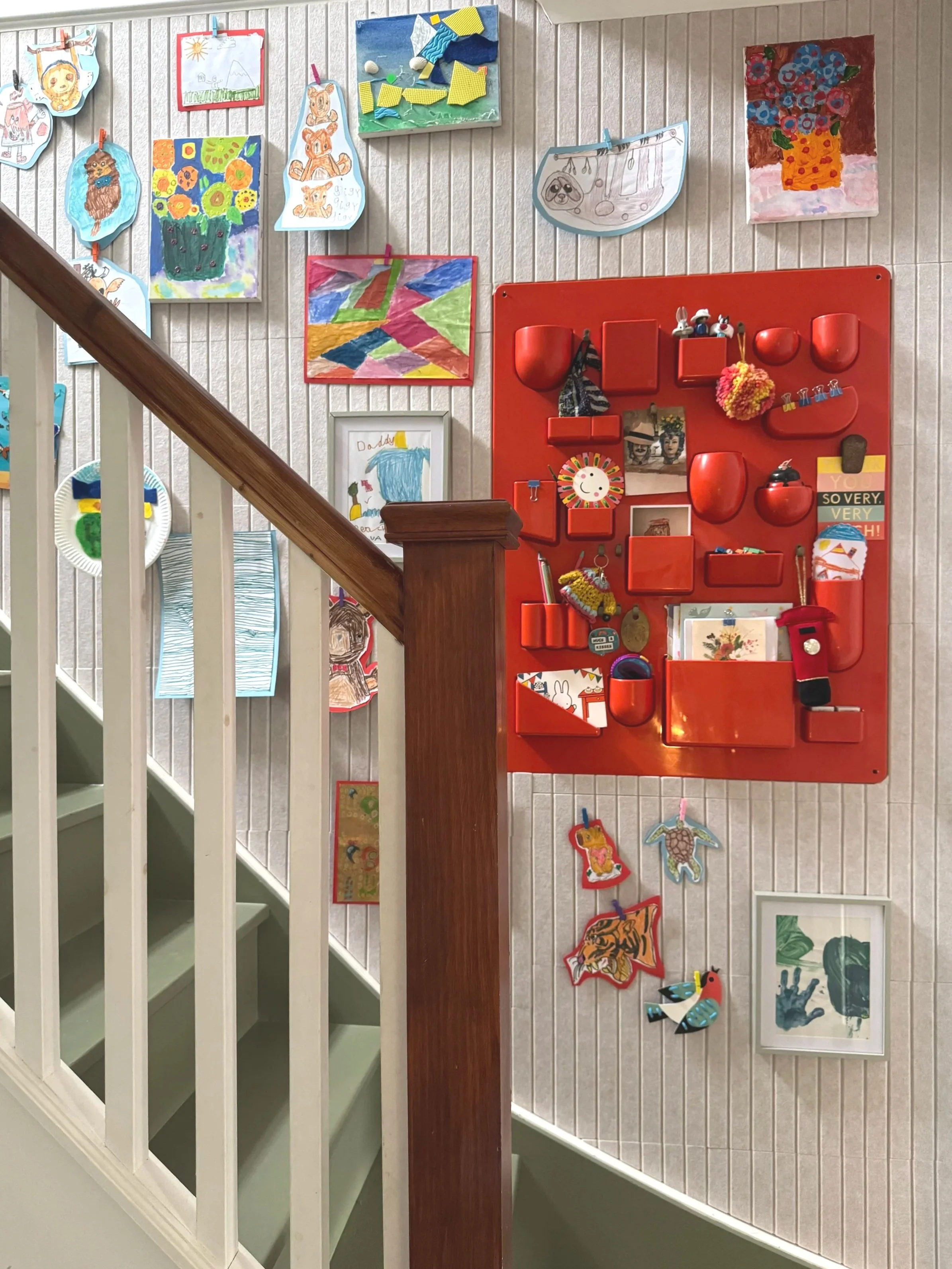 Staircase wall covered in art with green painted stairs and orange feature organiser