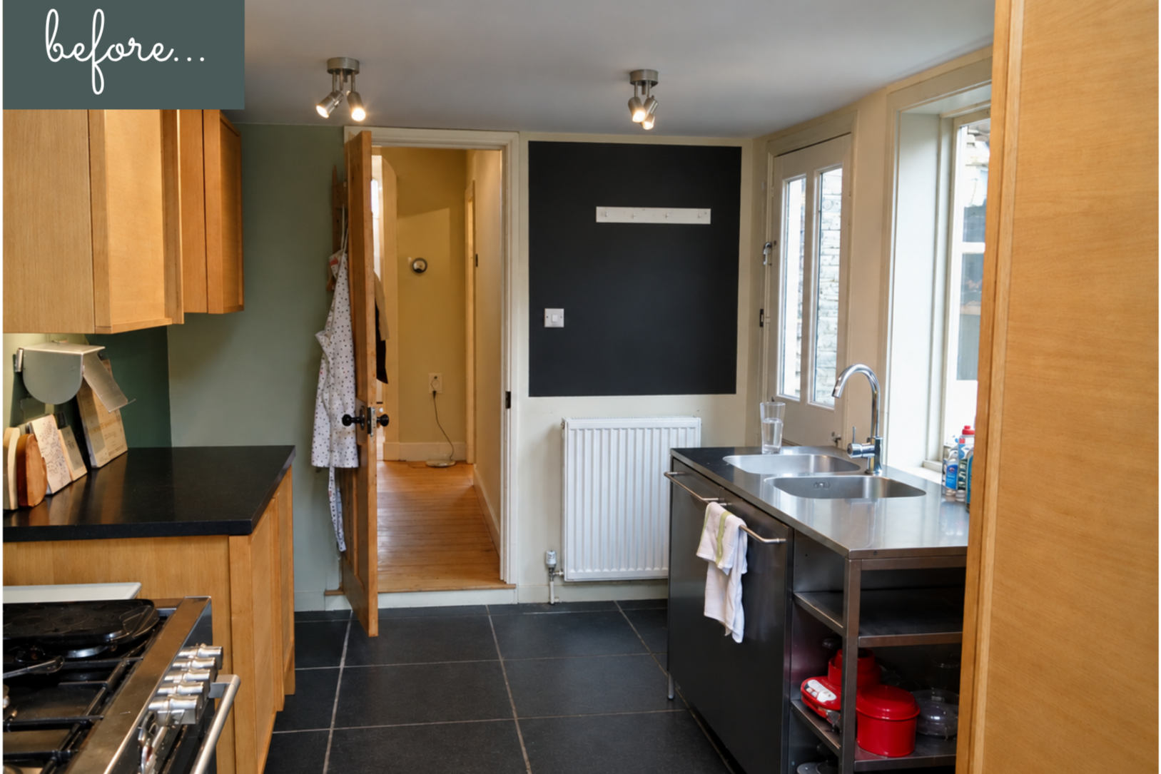Kitchen with dark grey tiled floor,  wooden cupboards and green wall
