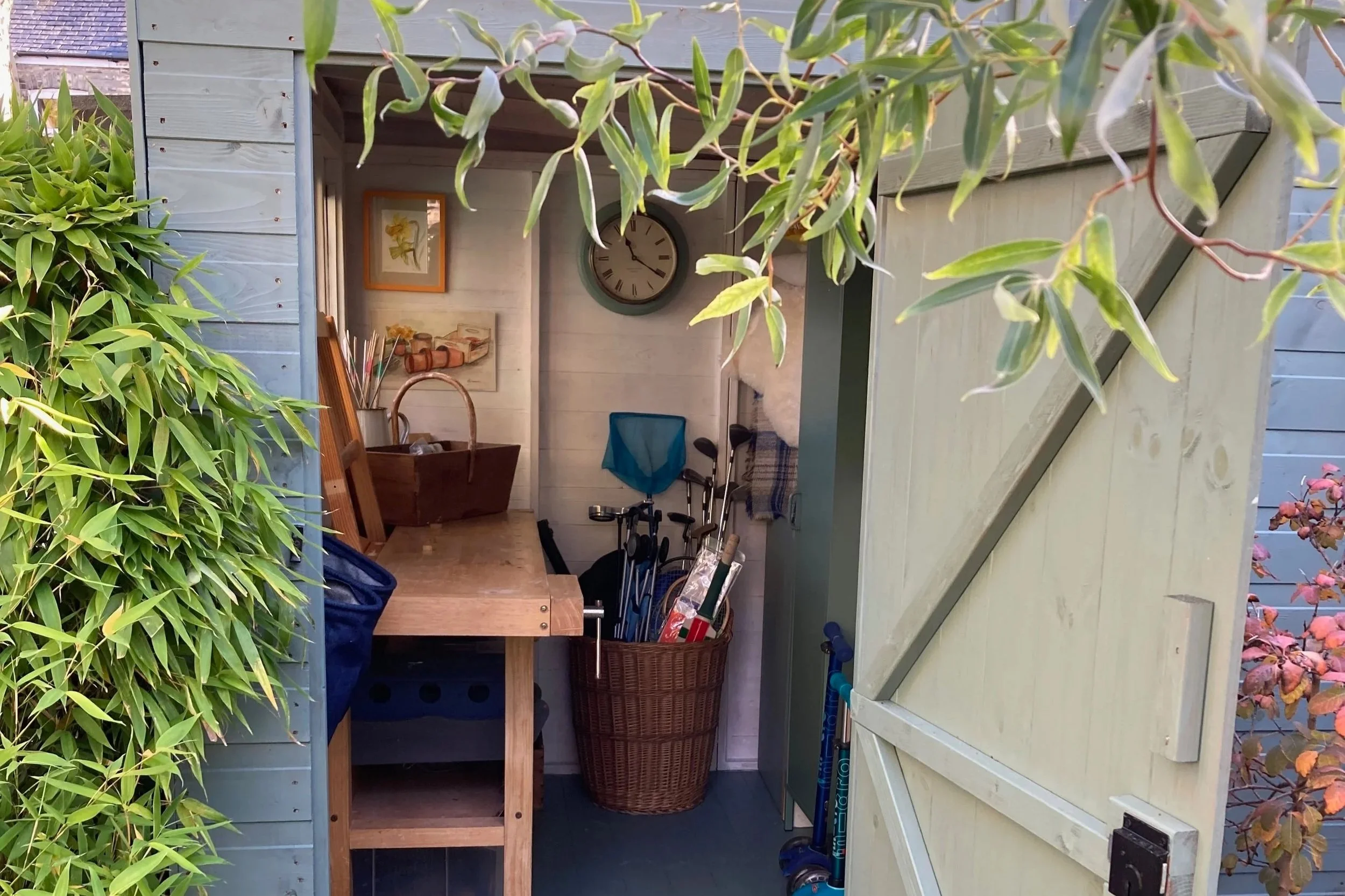 view into shed with green door, workbench, clock and sports equipment in the shed
