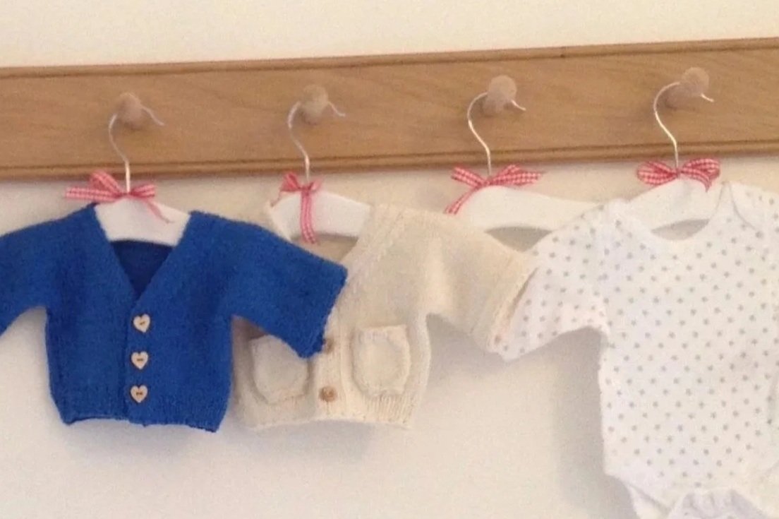 Baby clothes hanging on wooden peg rail