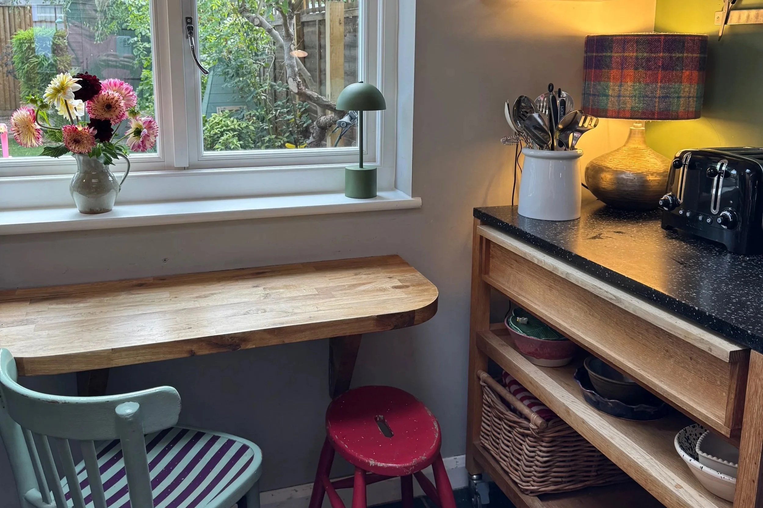 Small oak kitchen table in folded up position with red stool and striped chair