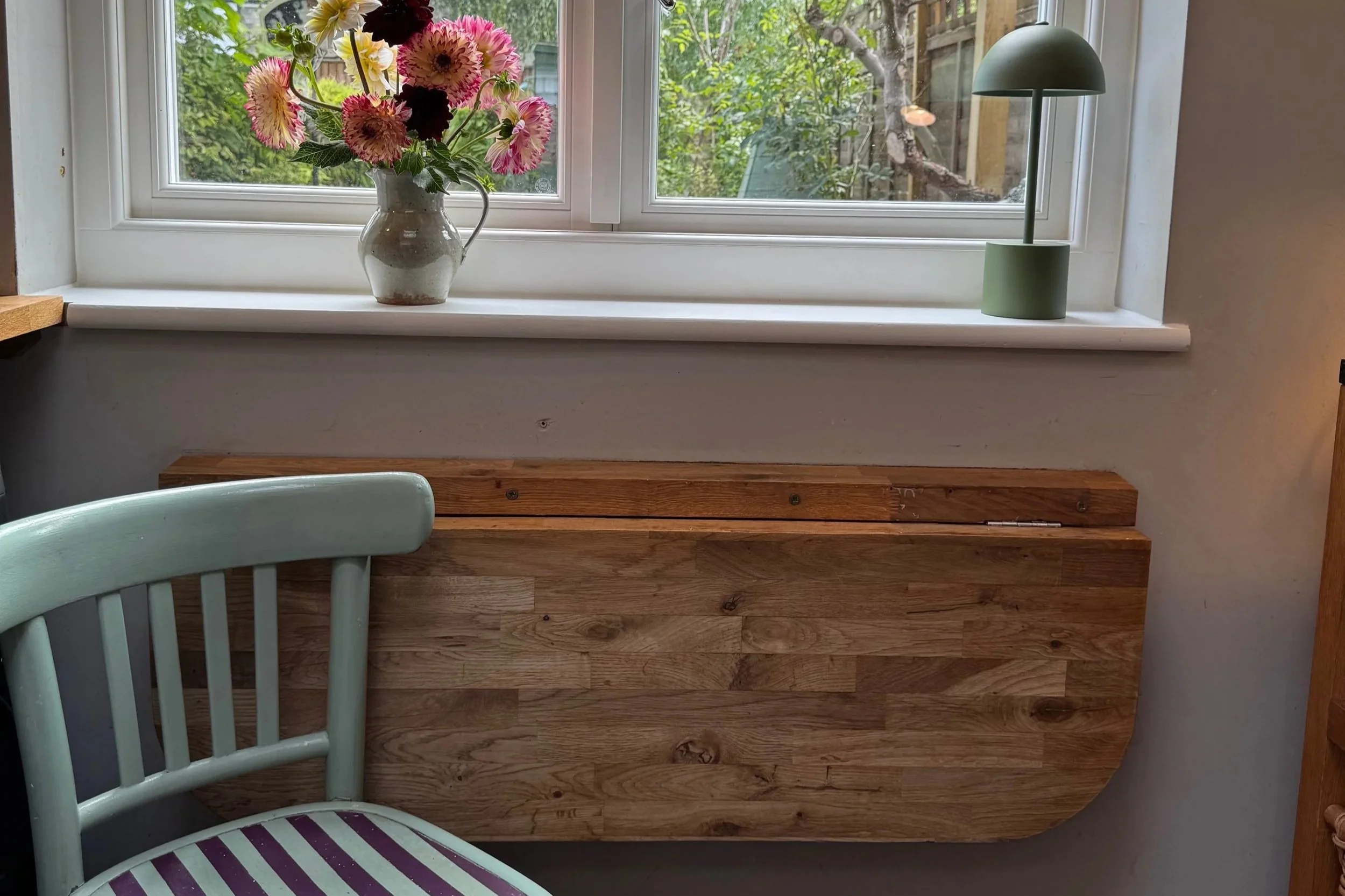Fold down oak table under window with chair painted in green and purple stripes