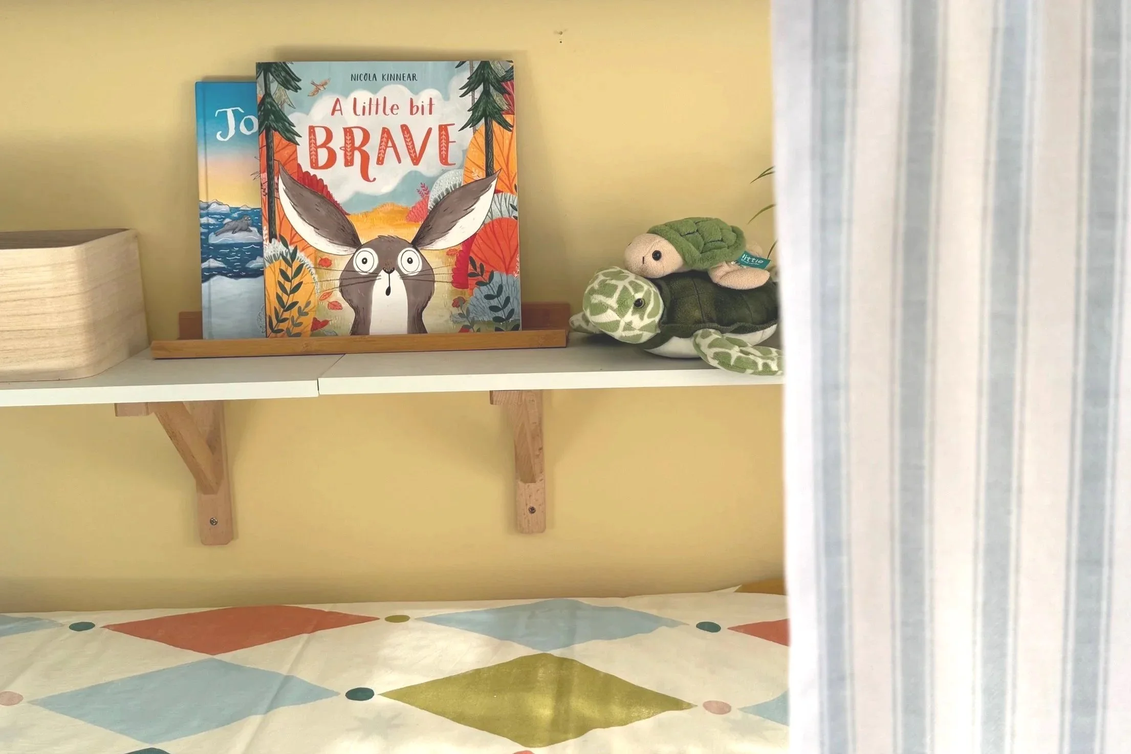 Shelf and duvet colour in yellow and green with children's books and toys on shelf