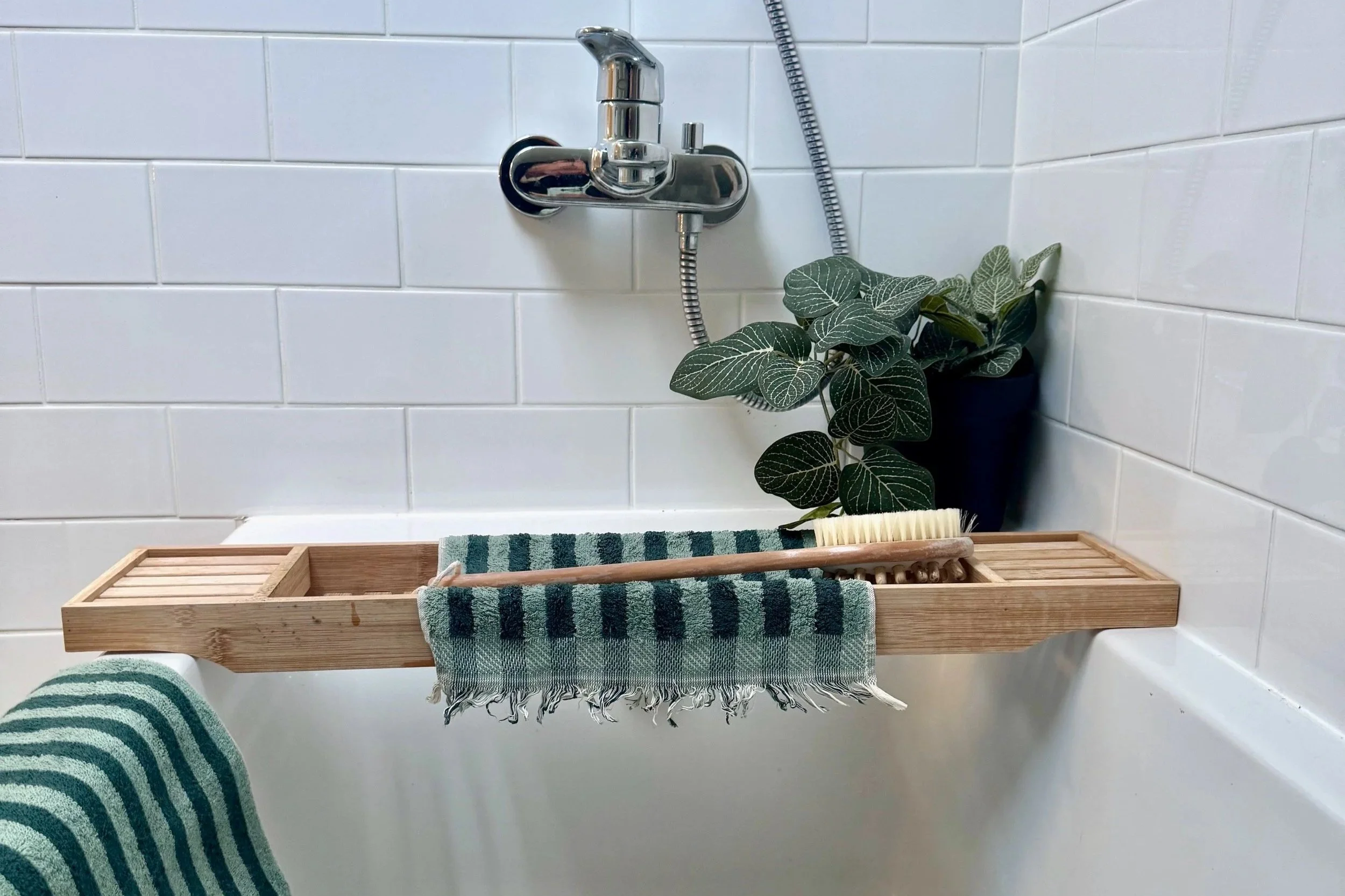 Bath with green stripe towels and plant