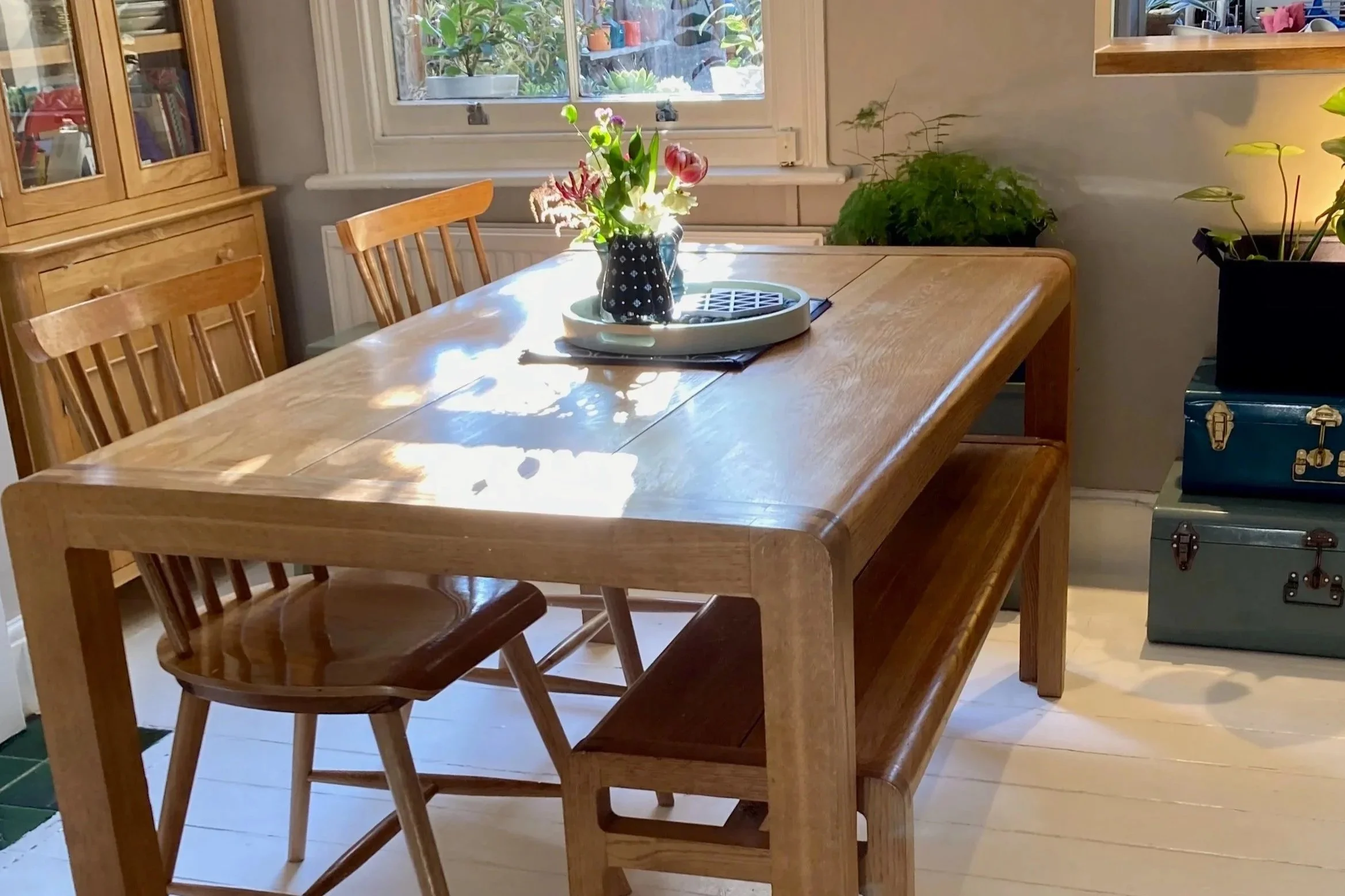 Wooden dining table and chairs with flowers and white painted floor