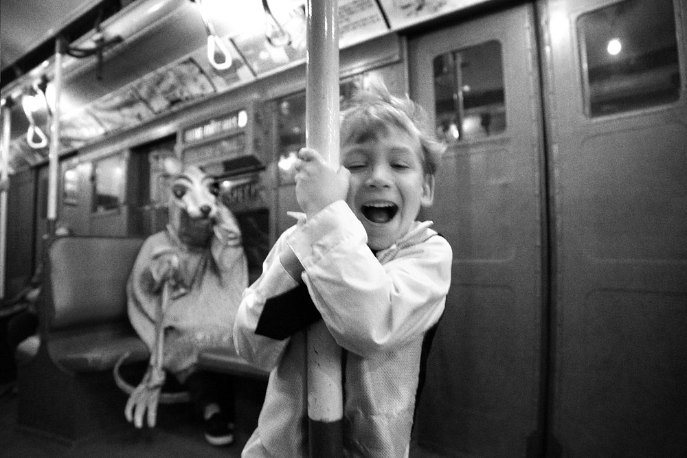Joyful little boy riding the NYC subway with his invisible friend