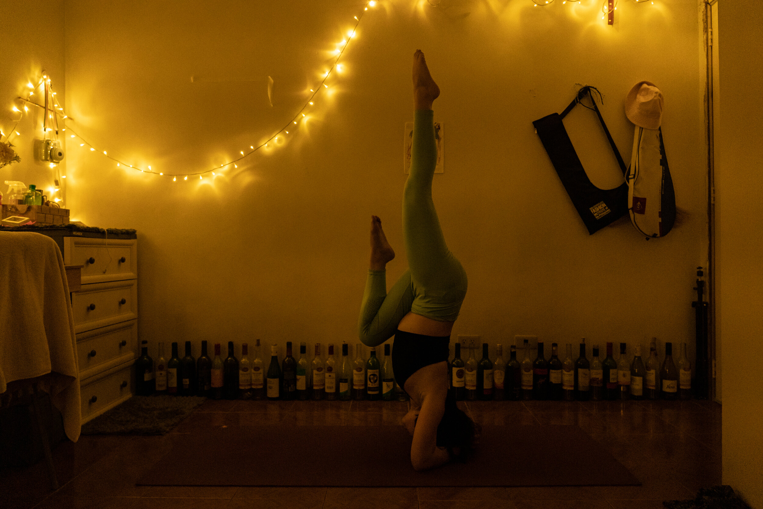  Karla Longjas, 27, does a headstand during meditative yoga inside her room, which is filled with bottles of alcohol. Apart from her medications, she practices yoga to have mental clarity, calmness, and stress relief. 
