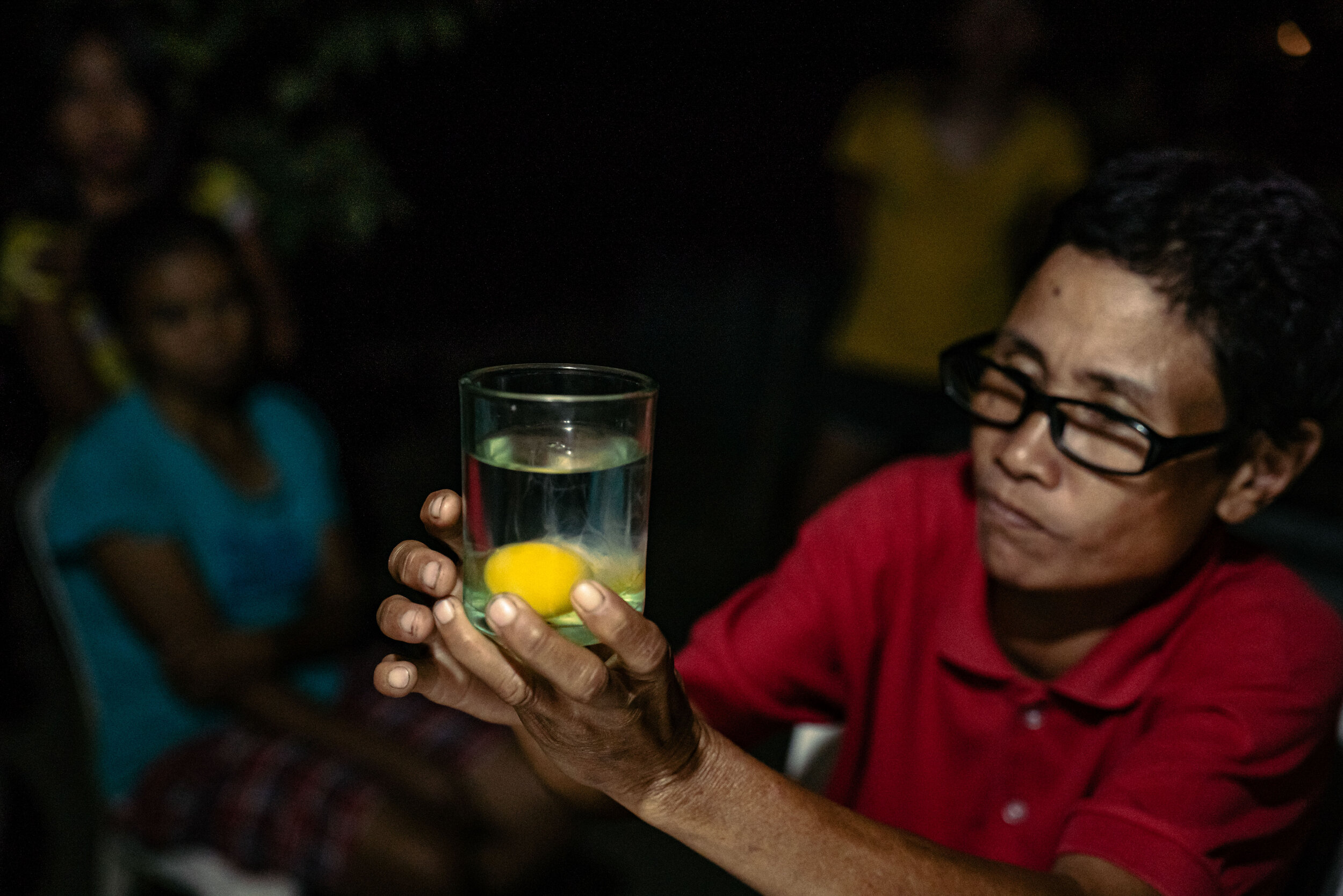  Nida Cautidar, a local healer from Sitio Kalangitan, performs a diagnostic ritual by cracking a raw egg into a glass of water to be examined for any change in shape that might suggest the nature of one’s illness. Nida learned these healing practices