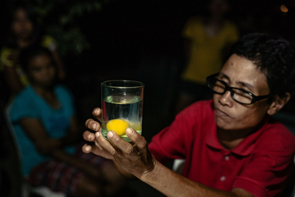  Nida Cautidar, a local healer from Sitio Kalangitan, performs a diagnostic ritual by cracking a raw egg into a glass of water to be examined for any change in shape that might suggest the nature of one’s illness. Nida learned these healing practices