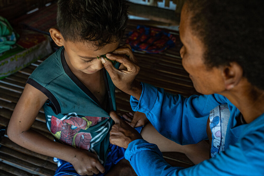  Lily De Guzman presses on hagonoy leaves mixed with salt onto her grandchild's forehead after he shows flu symptoms. Lily and the Aeta community of Sitio Gayanon firmly believe that the hagonoy plant keeps them safe from the Covid-19 pandemic. 