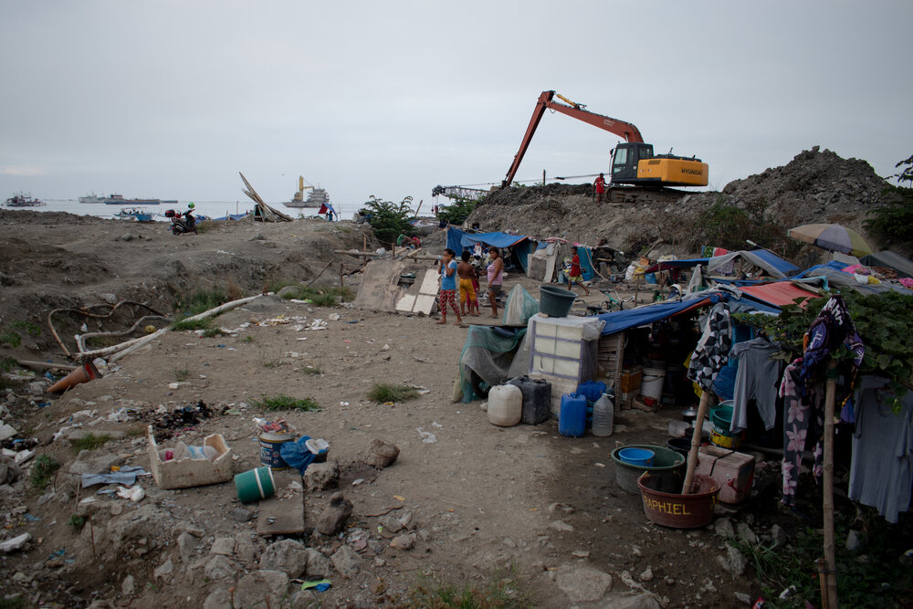  A backhoe used for reclamation sits idle on top of dirt. In this area alone, there are 10 families taking shelter in makeshift tents, all of them fisherfolk who depend on the sea for daily subsistence. Some families staying here are also from the re