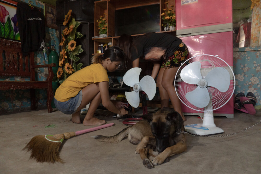  Lucila's nieces Jessilyn and Trixxie clean the house before they open their food stall at Smokey Mountain in Manila on March 17, 2021. Lucila says her husband, son, nephew, and nieces help keep the house clean. They also take turns manning the food 