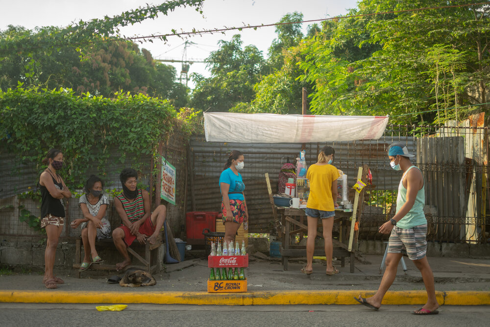  Lucila, her nieces, and neighbors attend to their food stall at Smokey Mountain in Manila on March 17, 2021. They pooled their resources to set up the small food stall so they could earn money during the pandemic. 