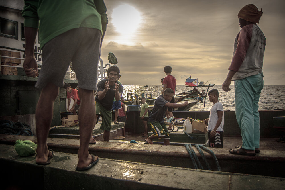  A fishing vessel goes side by side with another ship to transfer and trade supplies. Some fishermen stay at sea for weeks at a time to trade with those coming from the port. 