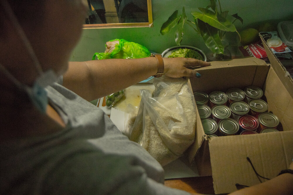  Back in Manila, Susan Melindo, 50, opens a food pack from the local government. The food pack contains 18 assorted canned foods and 3 kilograms of rice. They receive one pack at least once a month. 
