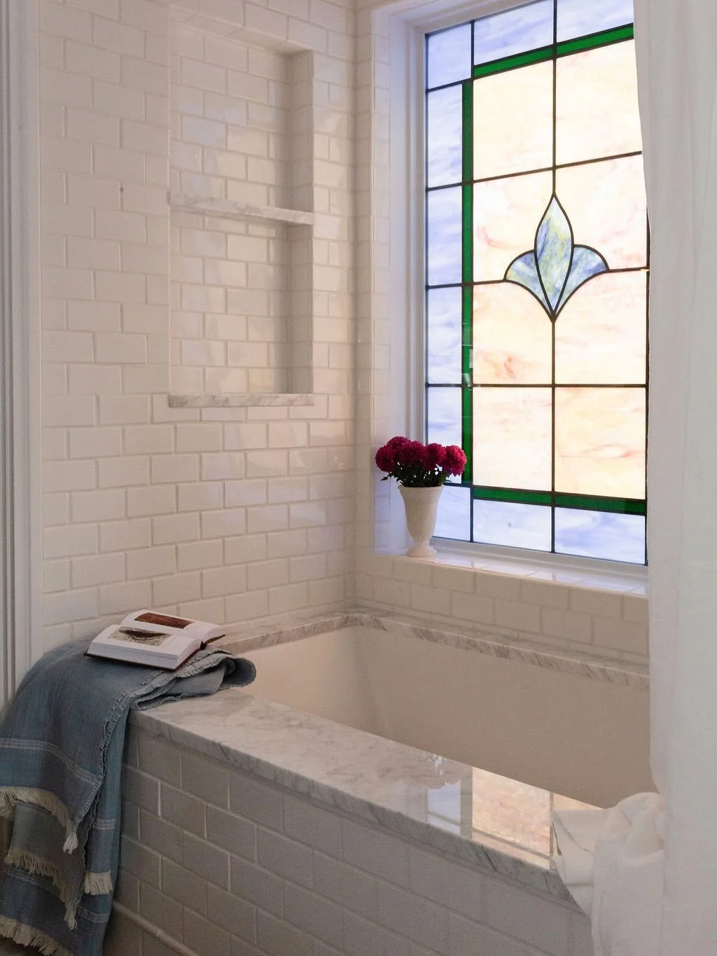 A large, existing window once posed a challenge for the new shower location&mdash;but it became an opportunity. In collaboration with William&rsquo;s Stained Glass, the family used existing windows from the first 
floor to design a custom stained gl