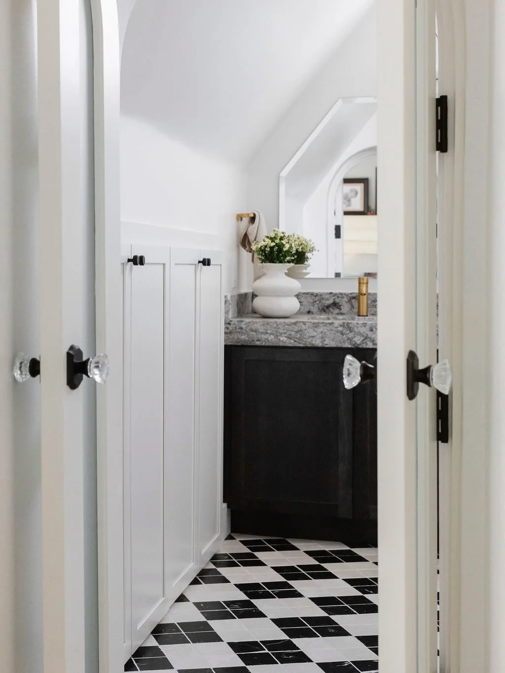 This arched opening into the primary bathroom originally had no doorway. We designed a custom French door to follow the architecture of the arch&mdash;adding privacy while maintaining an elegant transition between the bedroom and bath.

Photography b